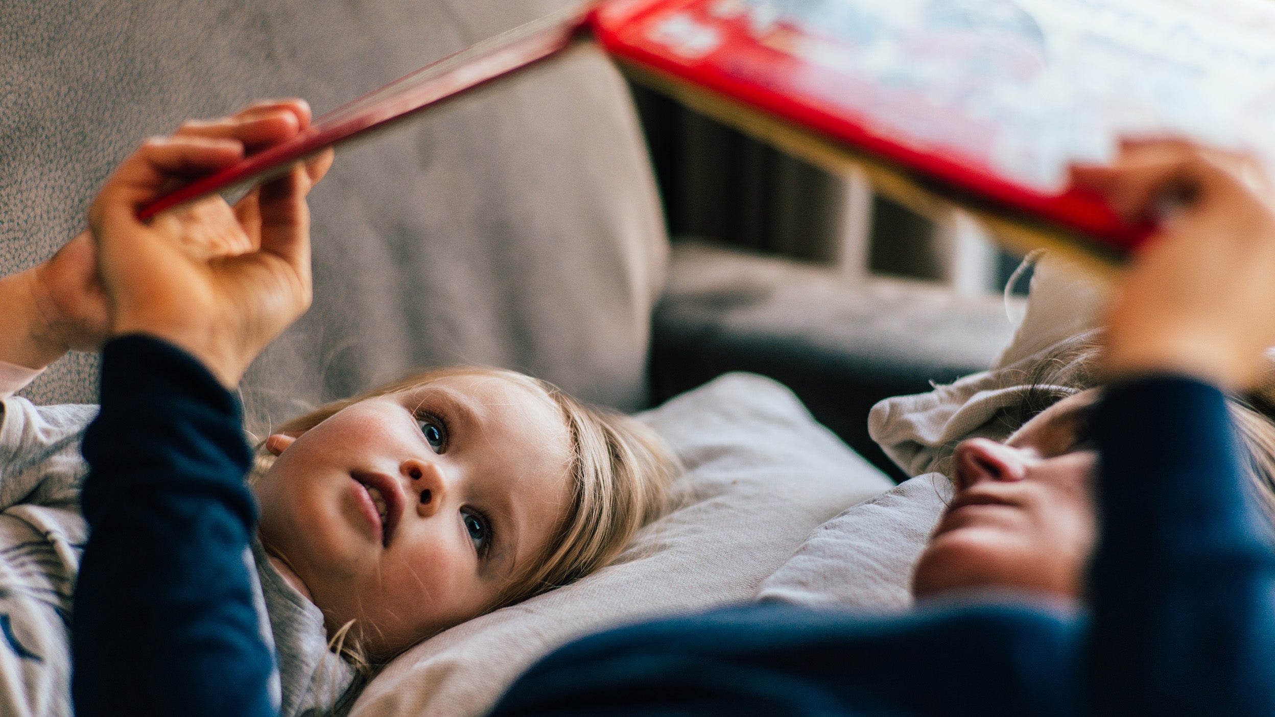 Young boy listening attentively to his mother reading a book