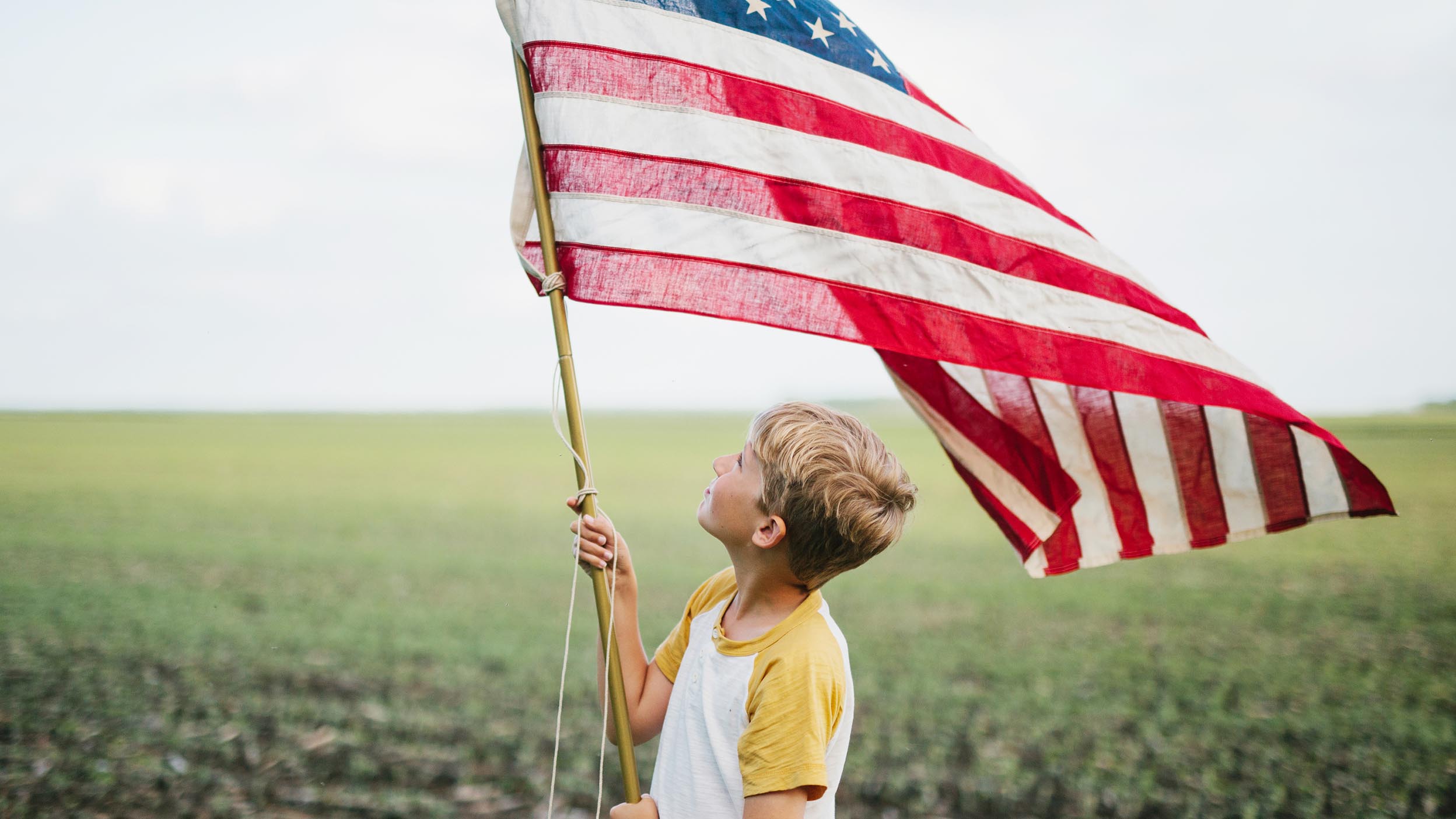 Boy looking up at large American flag
