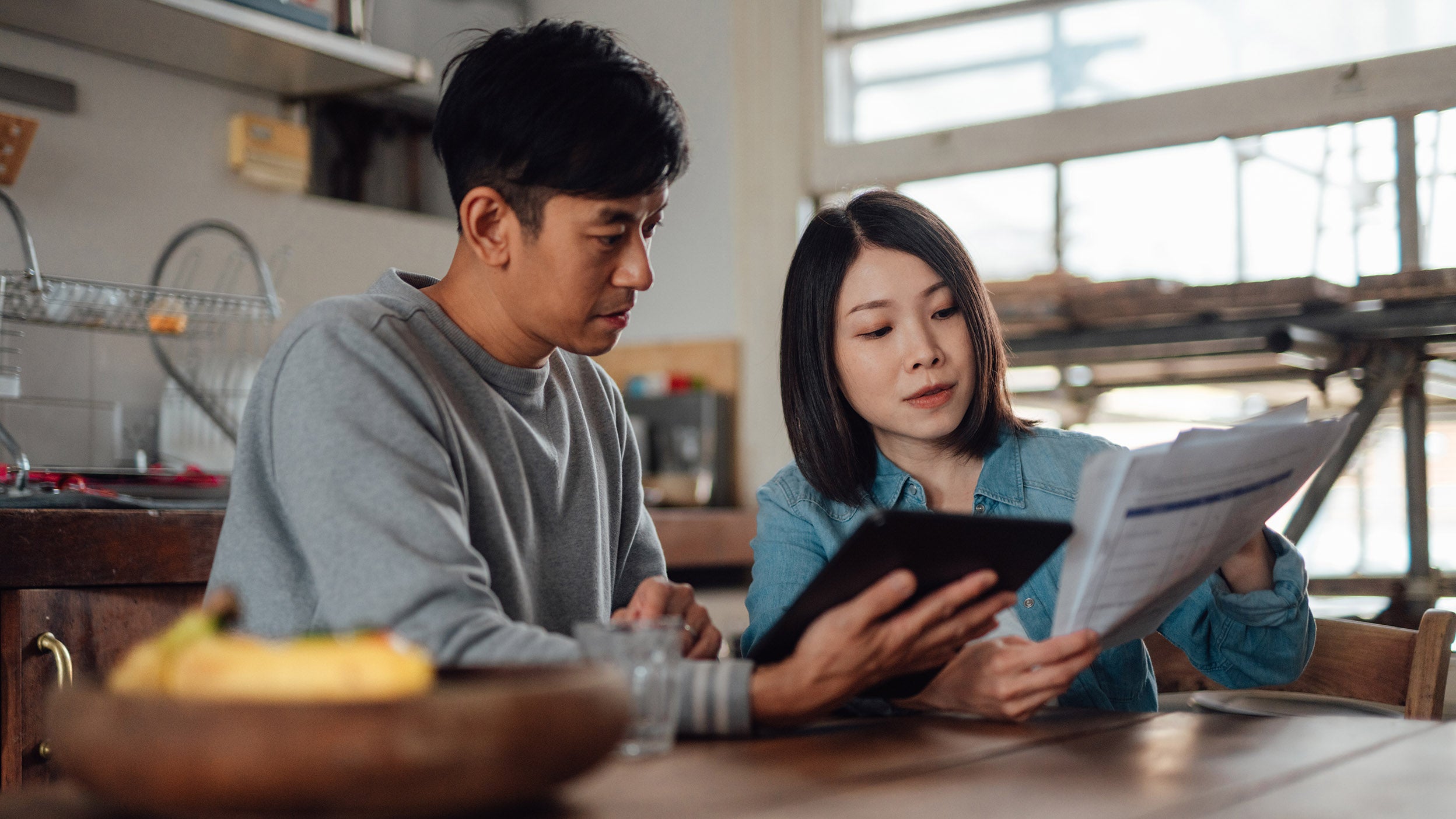 Asian couple going over taxes on their tablet.