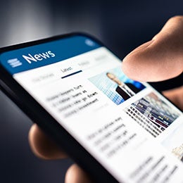 Close-up%20shot%20of%20a%20hand%20holding%20a%20phone%20with%20a%20news%20article%20on%20it.