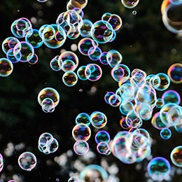 Rainbow%20soap%20bubbles%20from%20the%20bubble%20blower%20with%20trees%20in%20the%20background.
