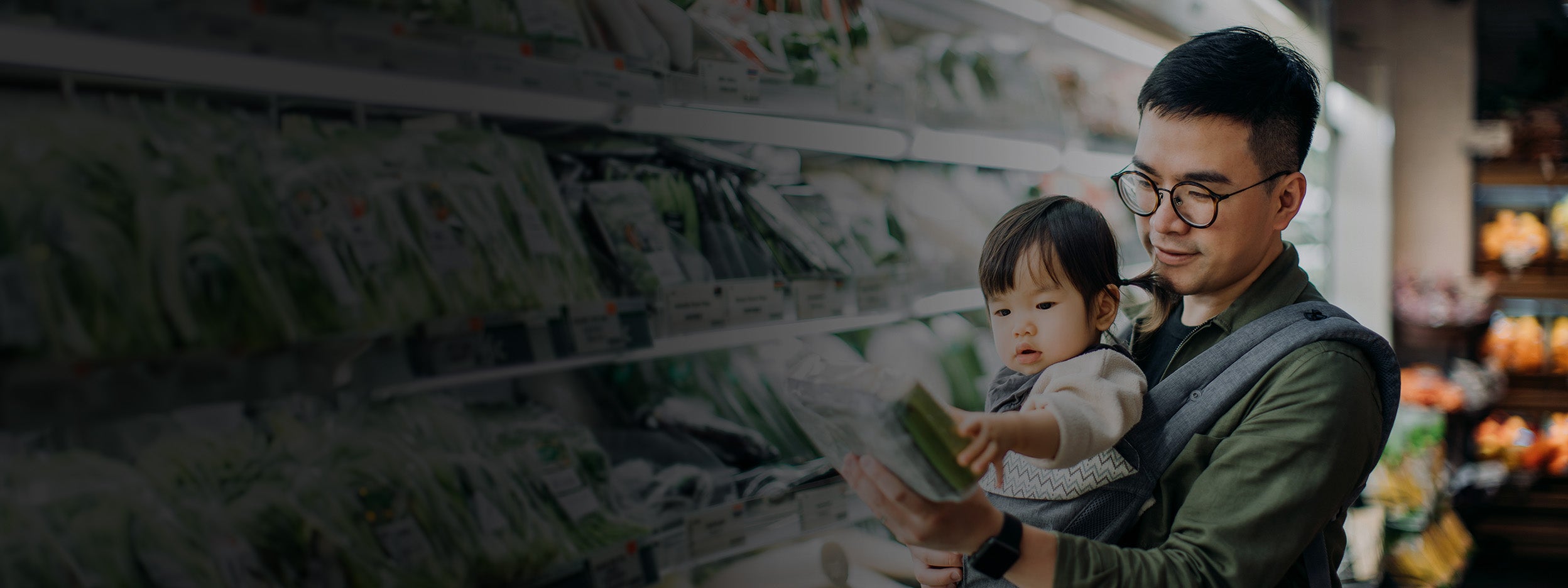 Un jeune père asiatique et sa jolie fillette font leurs courses au supermarché dans le rayon des légumes biologiques frais