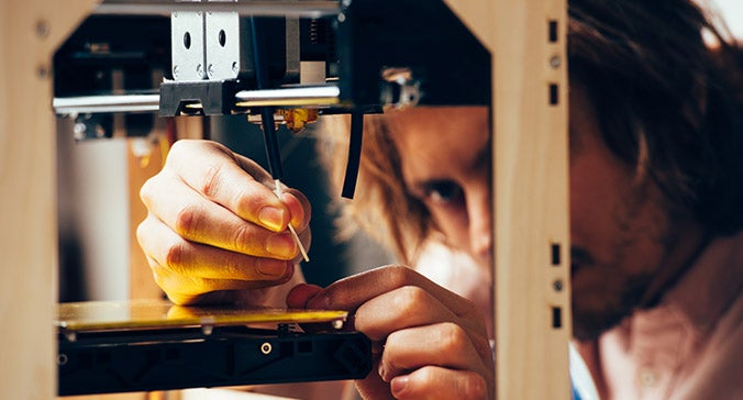 Man working closely with a 3D printer
