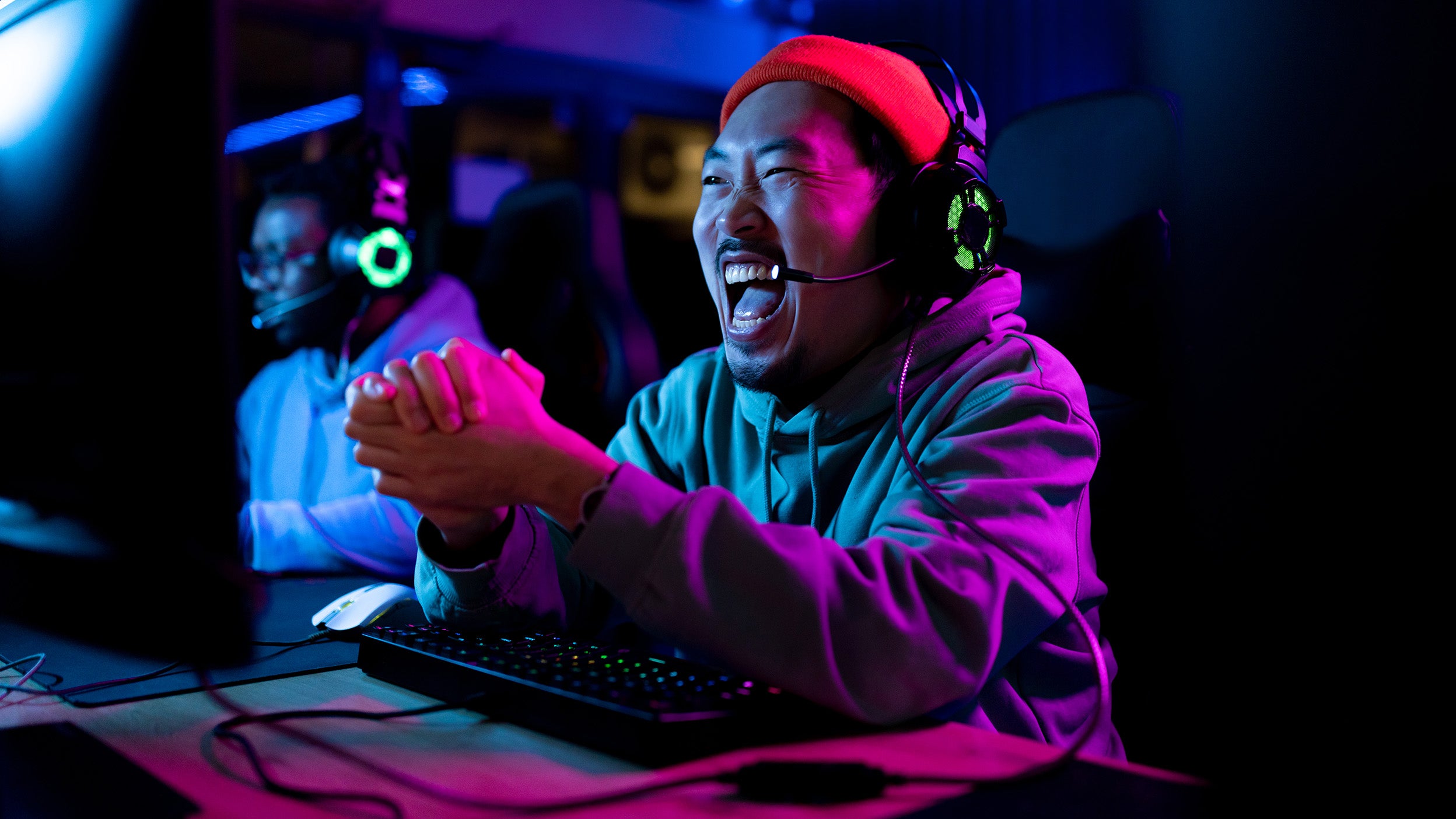 Man celebrates in front of a gaming computer, one of the technologies impacted by AI, which is reshaping companies within the underlying holdings of Invesco QQQ ETF. 