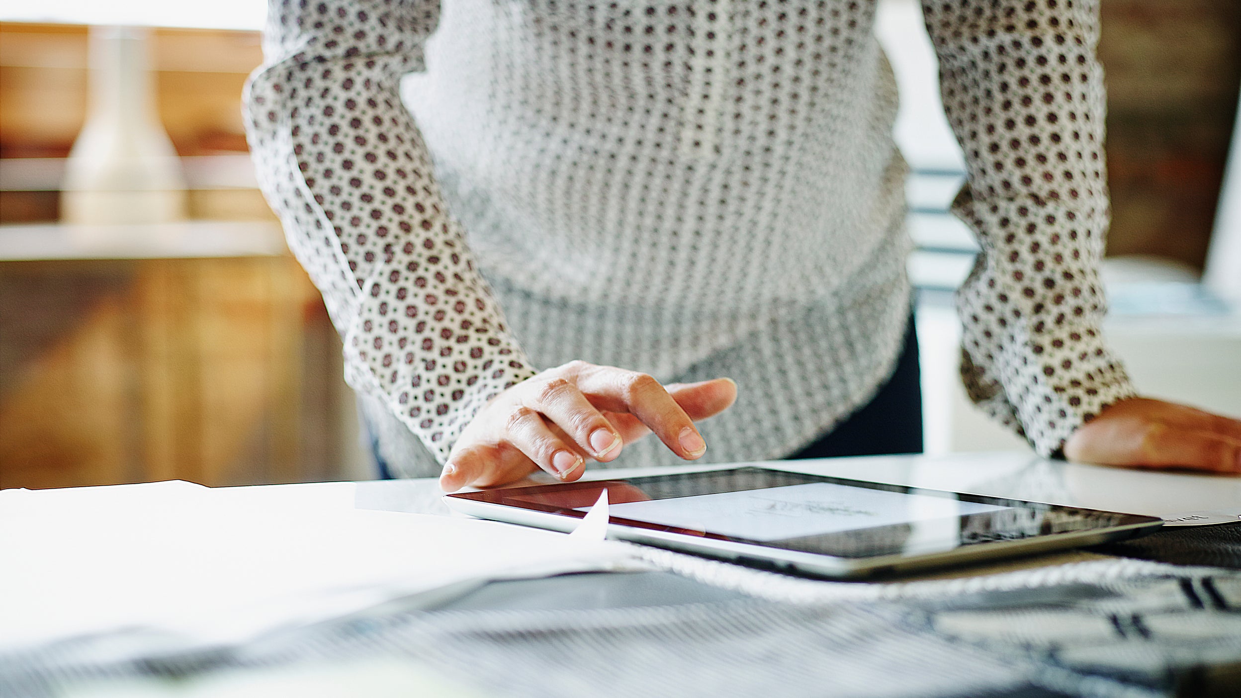 Image shows a user with a touchscreen device—to illustrate the ease with which individuals can invest in ETFs like Invesco QQQ. 