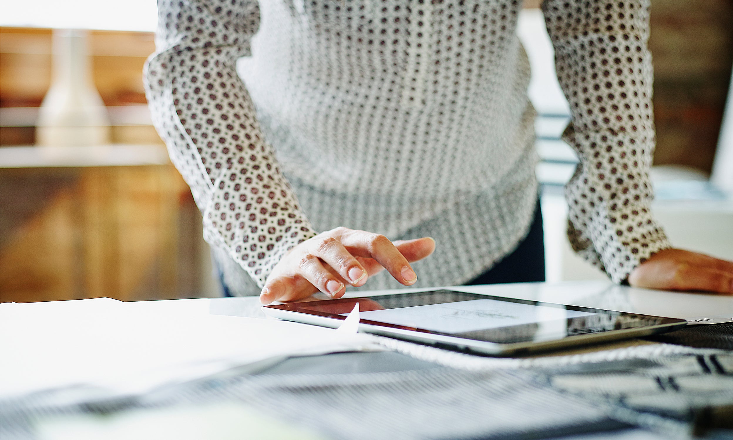 Image shows a user with a touchscreen device—to illustrate the ease with which individuals can invest in ETFs like Invesco QQQ. 