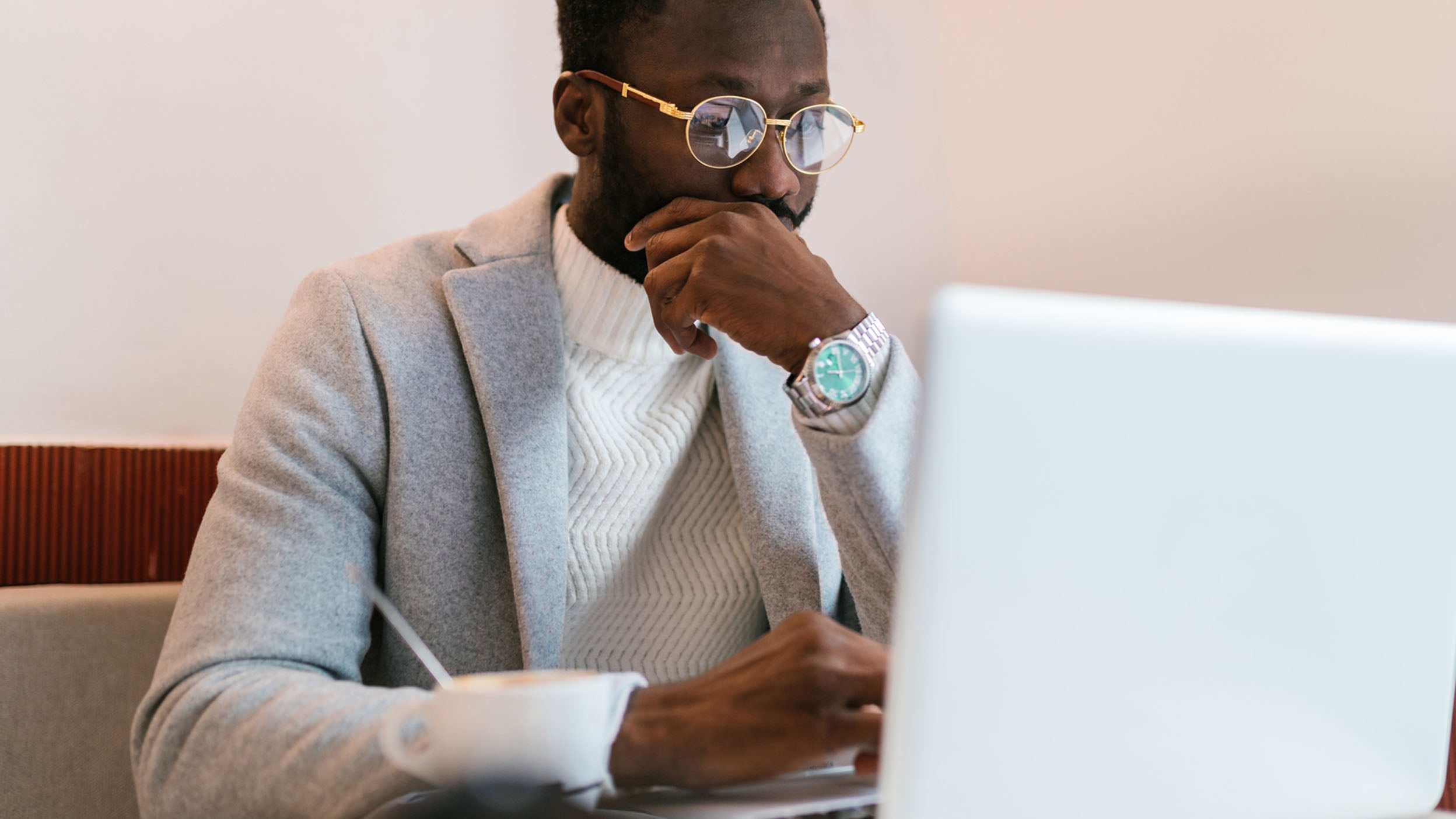 A man ponders a decision while looking at his laptop. Those who consider investing in ETFs, Link Invesco QQQ ETF, should know the possible risks.