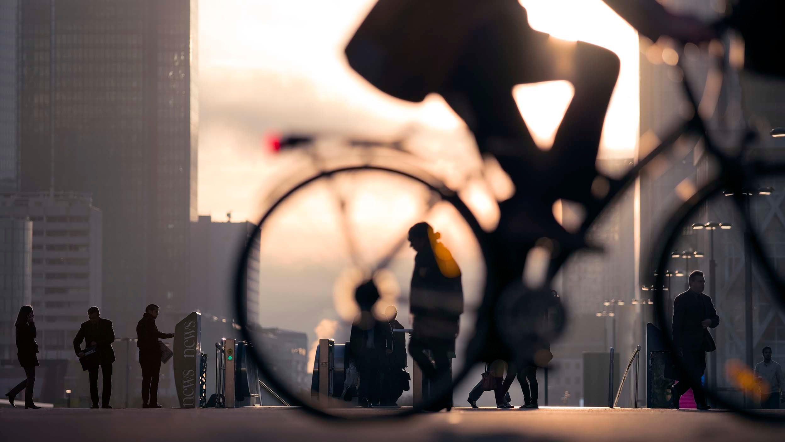 Morning image of businessman on bicycle passing skyline of La Defense business district in Paris, France.