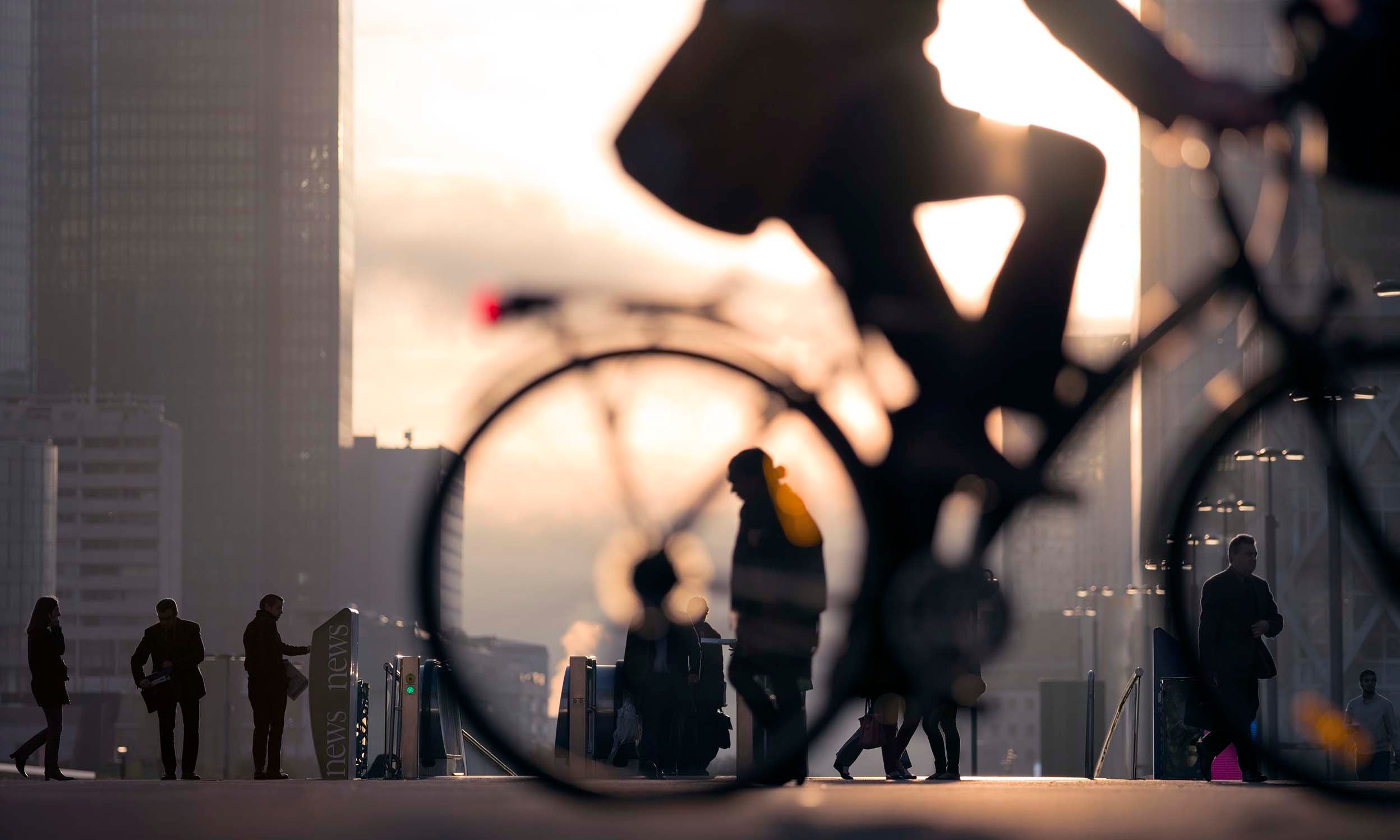 Morning image of businessman on bicycle passing skyline of La Defense business district in Paris, France.