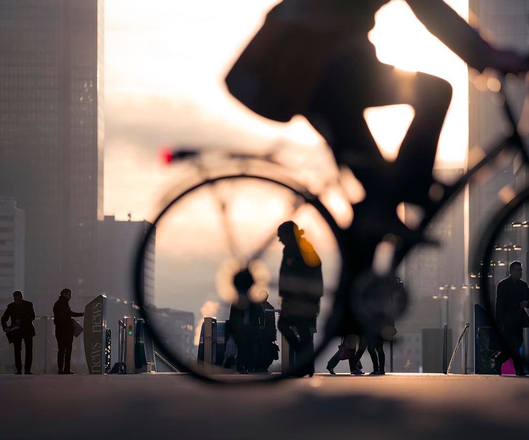 Morning image of businessman on bicycle passing skyline of La Defense business district in Paris, France.