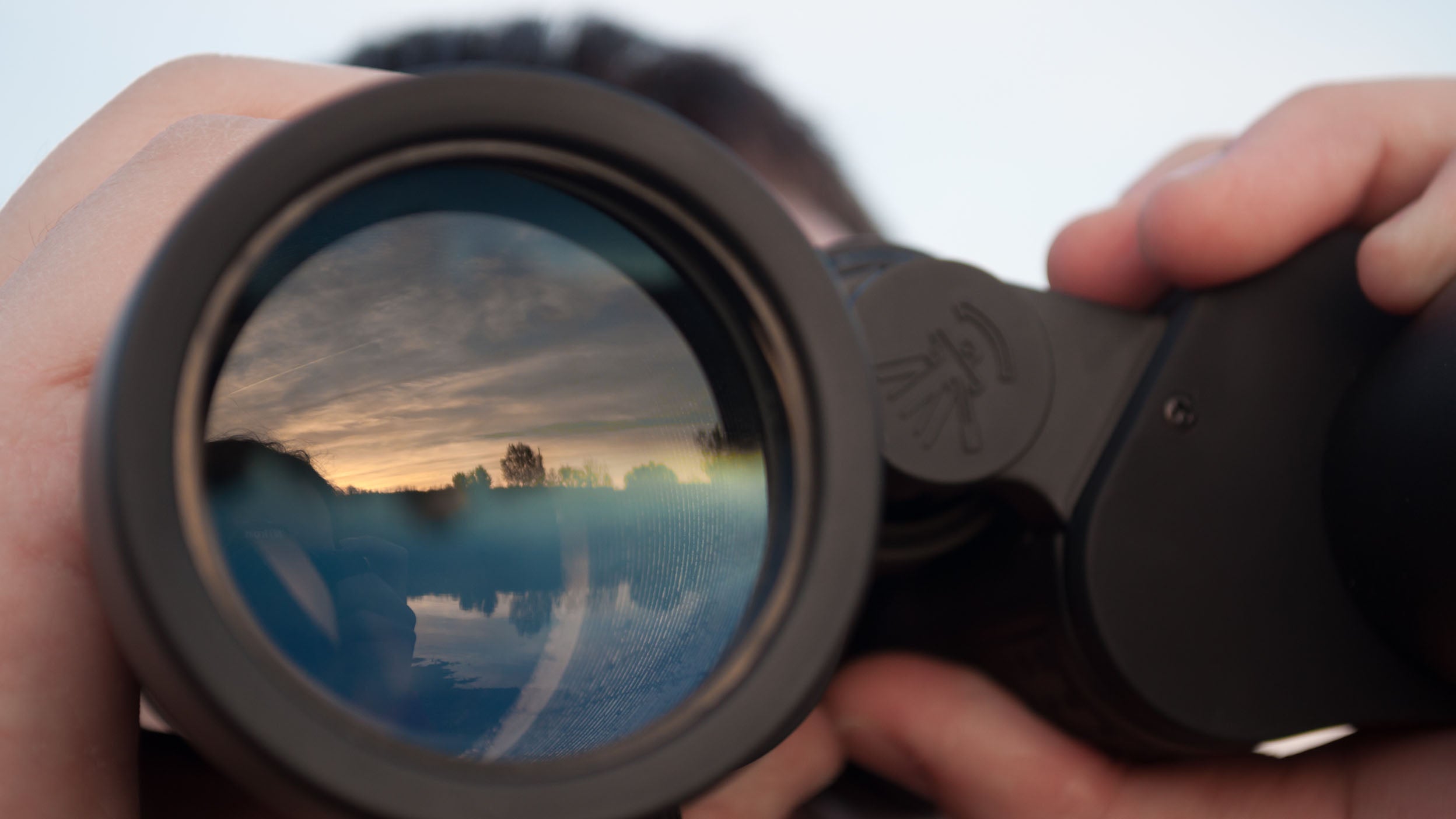 A person peering through binoculars represents an investor viewing the diversification within the companies that make up the Nasdaq-100 index.