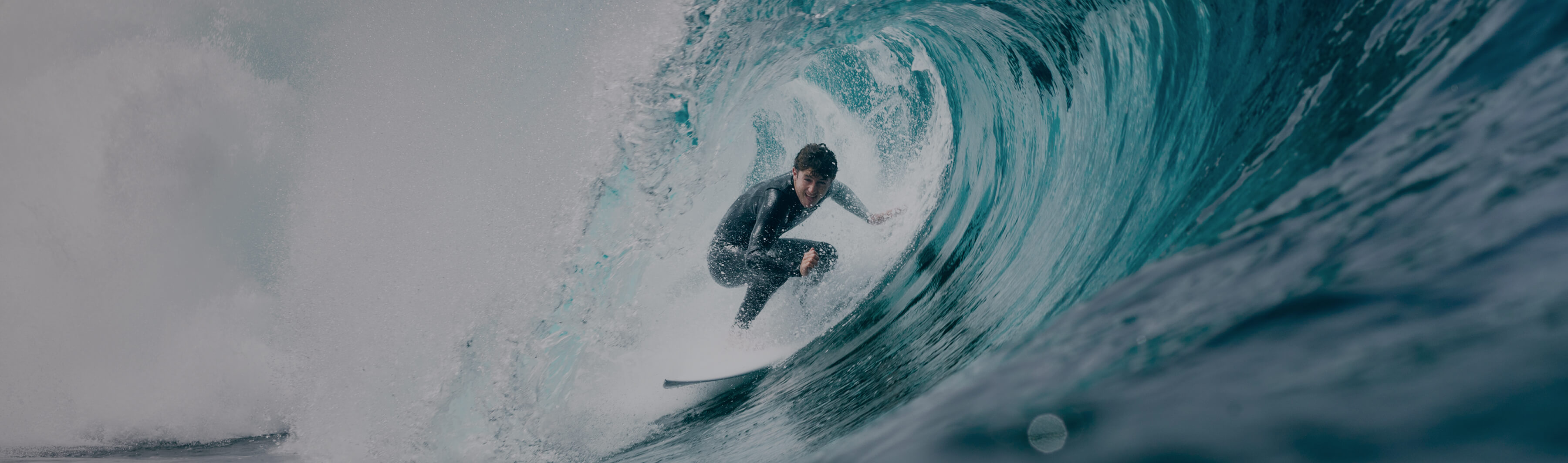 A surfer maintains perfect balance while riding inside the curling tunnel of a powerful ocean wave.