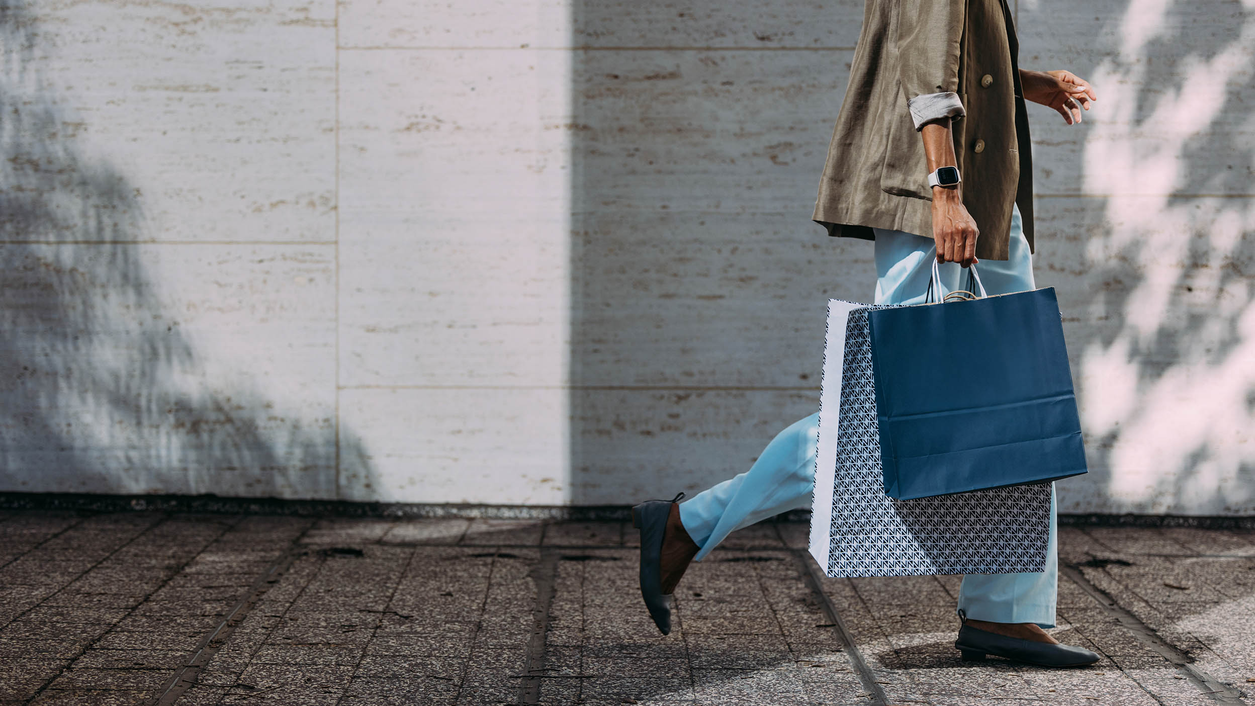 A person walks down the street holding shopping bags. Learn how consumer spending affects Invesco QQQ ETF