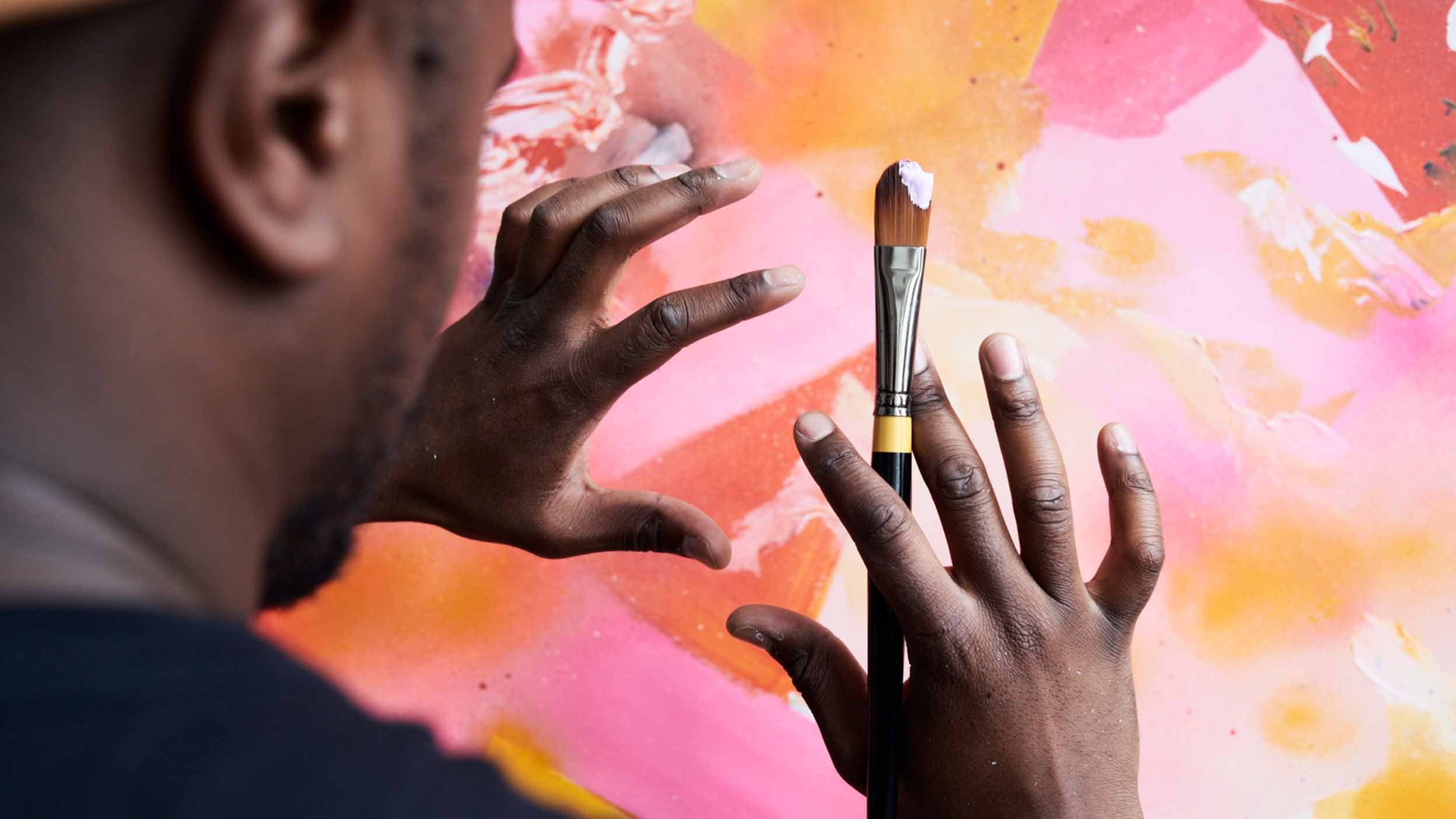 Back view of painter's hands measuring painted abstract canvas with hands.