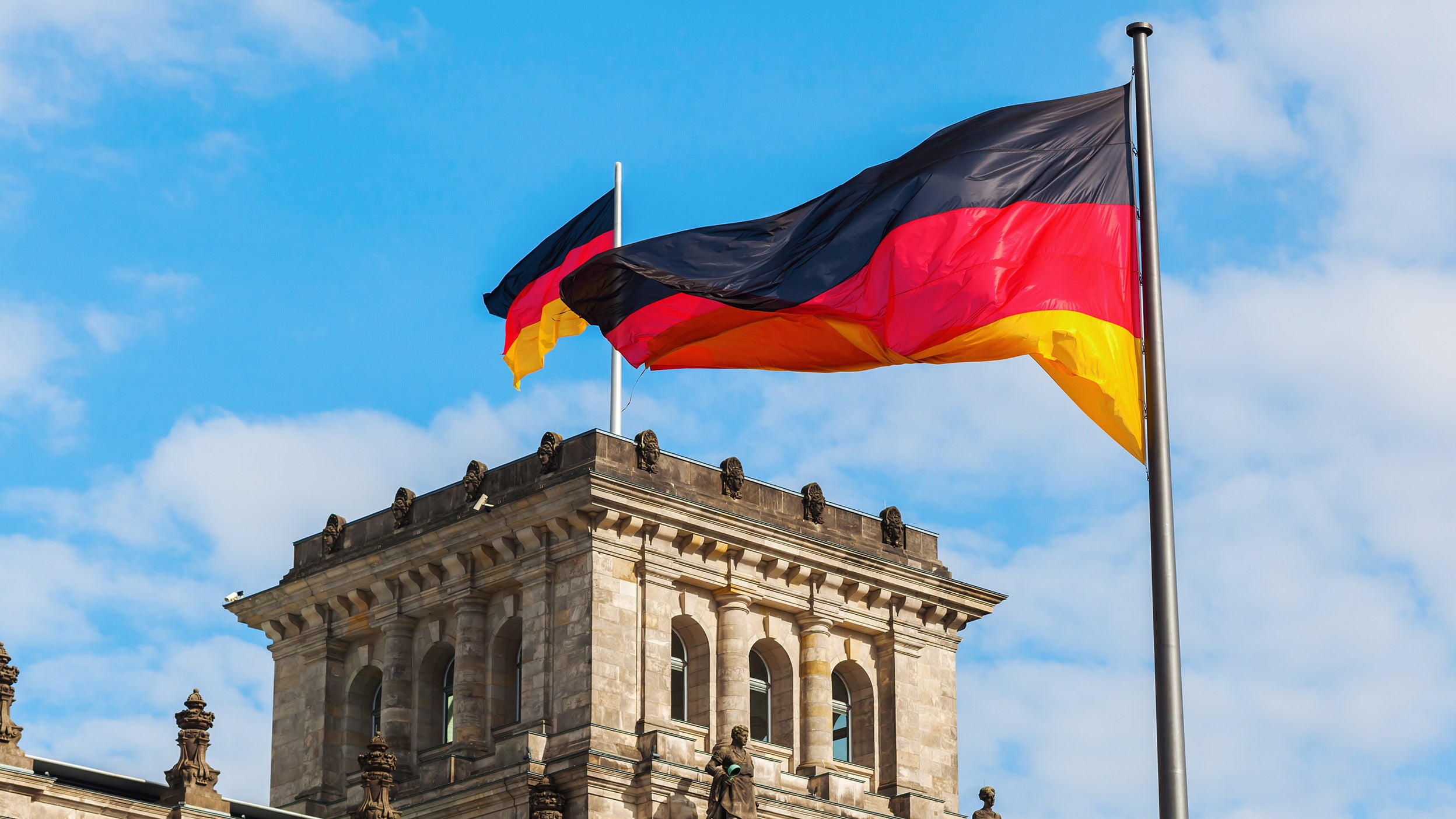 Vor einem Gebäude weht eine leuchtende deutsche Flagge, die mit der Architektur kontrastiert und die Szene aufwertet.