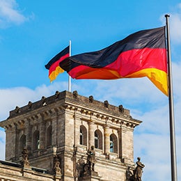 Vor%20einem%20Gebäude%20weht%20eine%20leuchtende%20deutsche%20Flagge,%20die%20mit%20der%20Architektur%20kontrastiert%20und%20die%20Szene%20aufwertet.