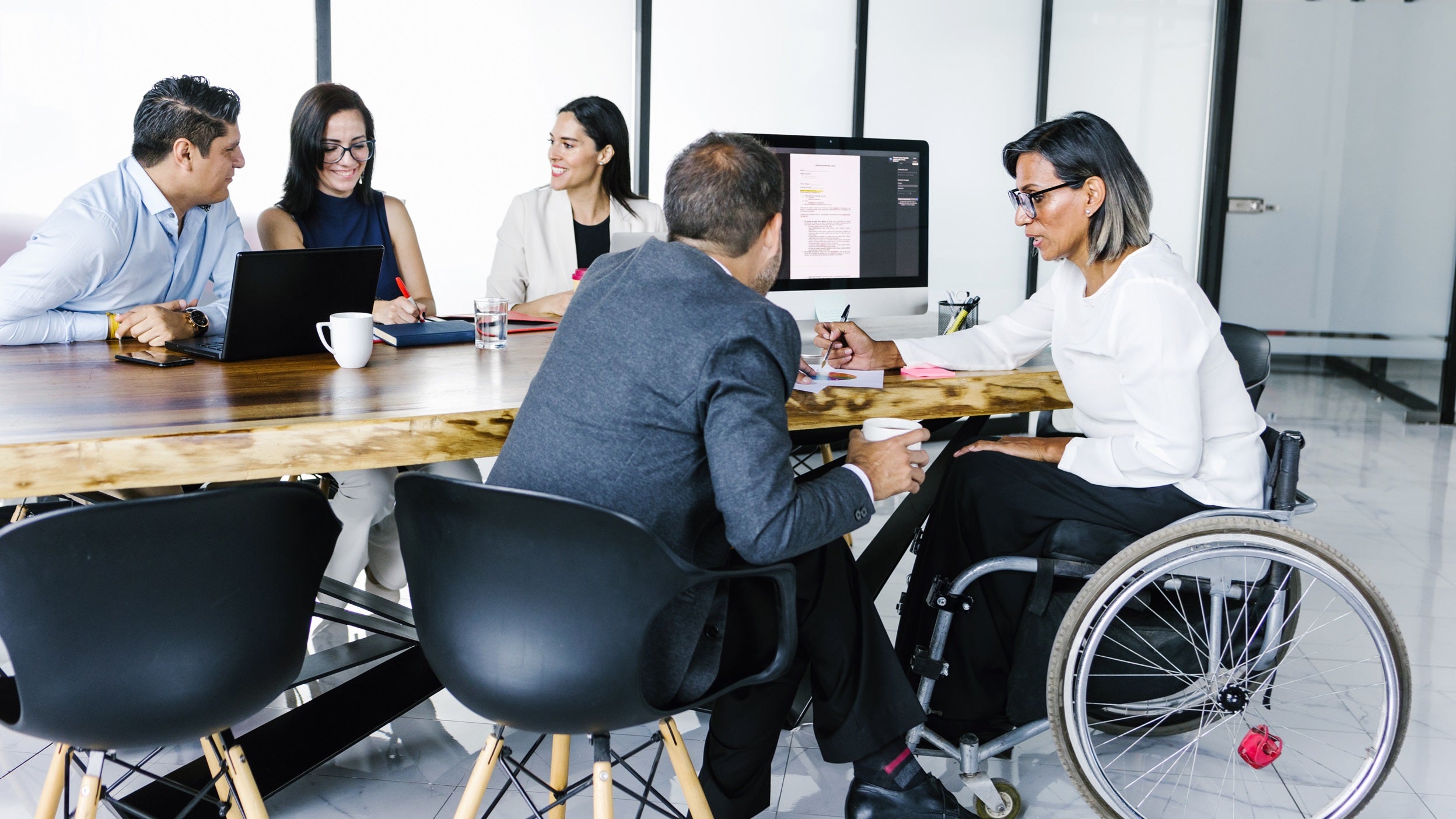 Businesswoman in wheelchair working on project with group of business people in office
