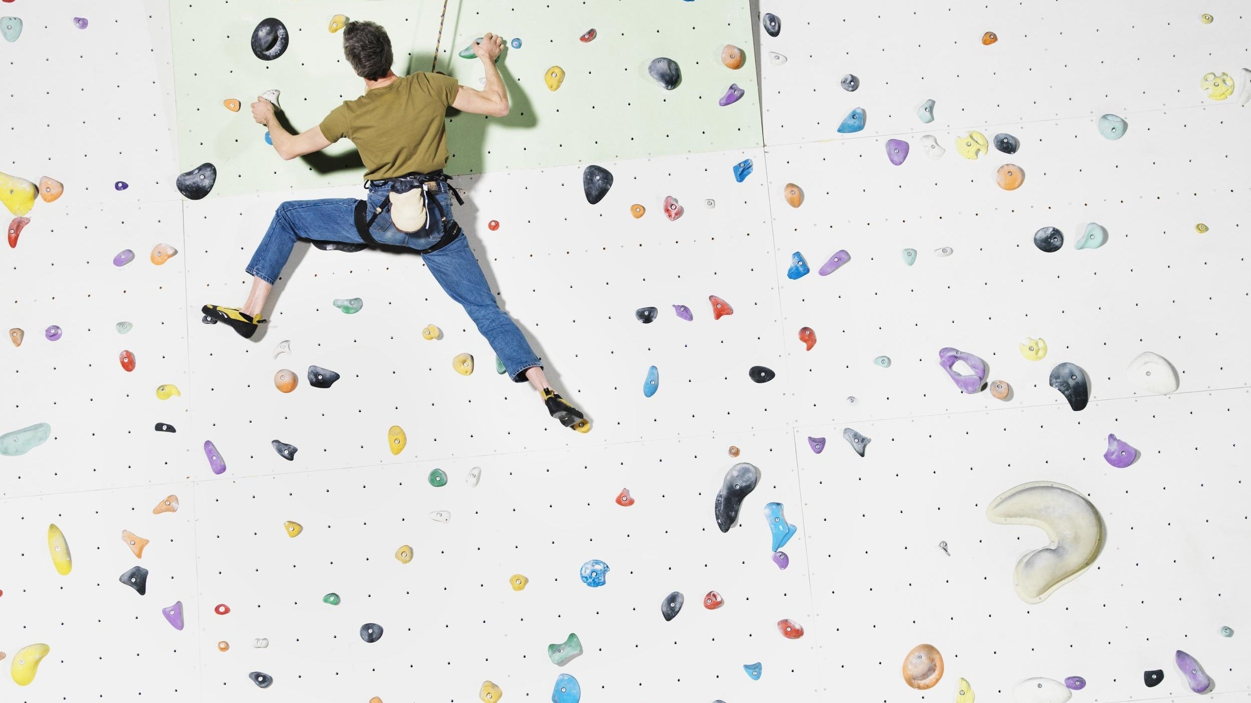 Man climbs up a climbing wall