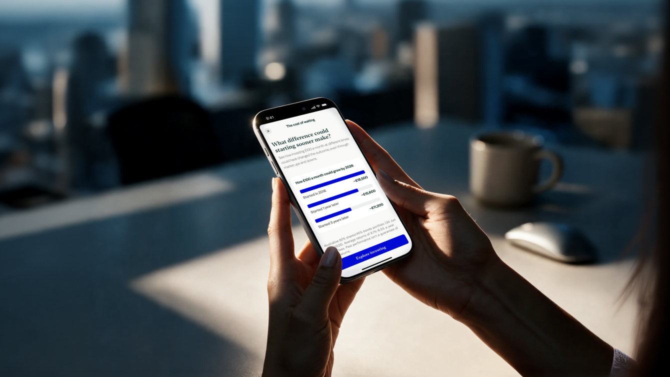 Someone holding a mobile phone, looking at the Invesco website on the screen