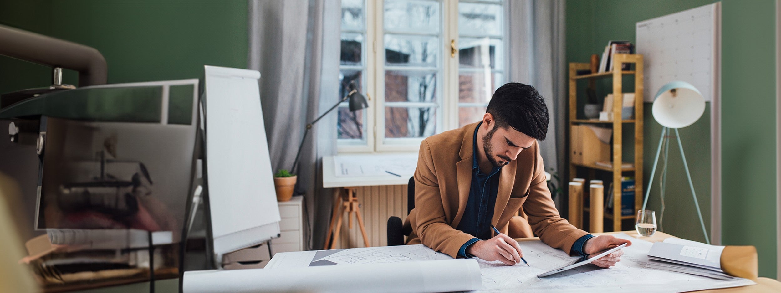 Person reviewing blueprints at a desk in a modern office