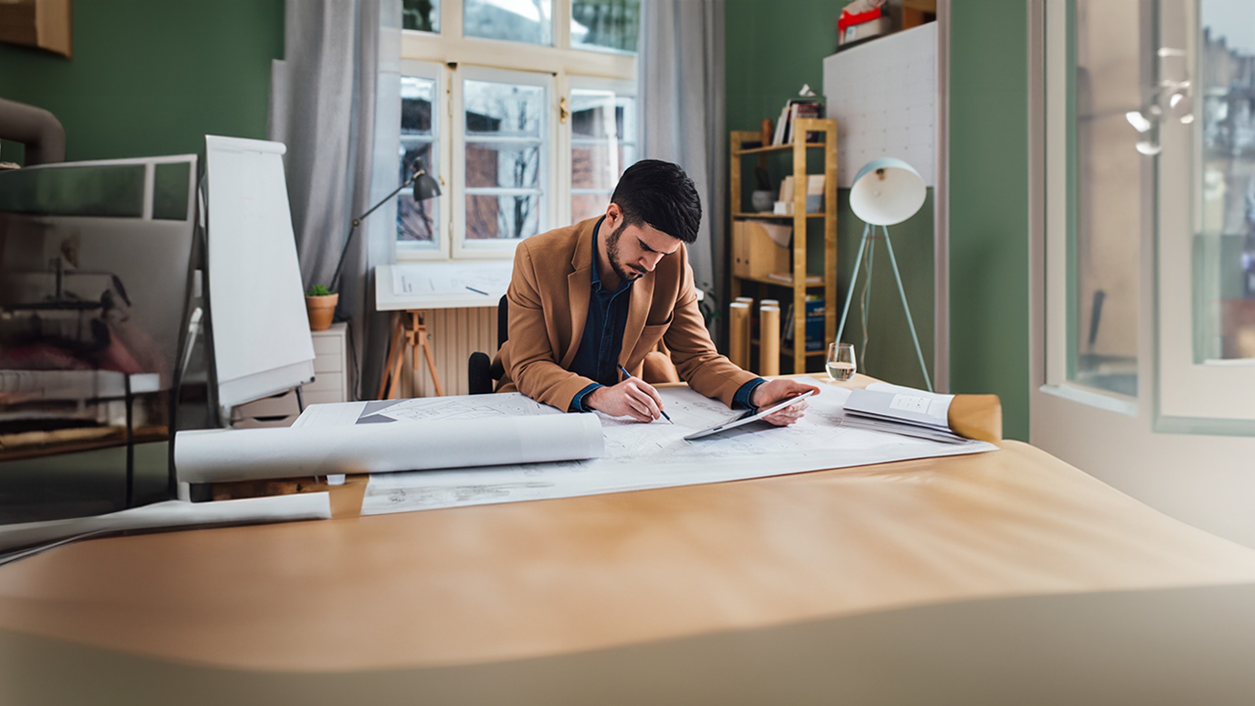 Person reviewing blueprints at a desk in a modern office