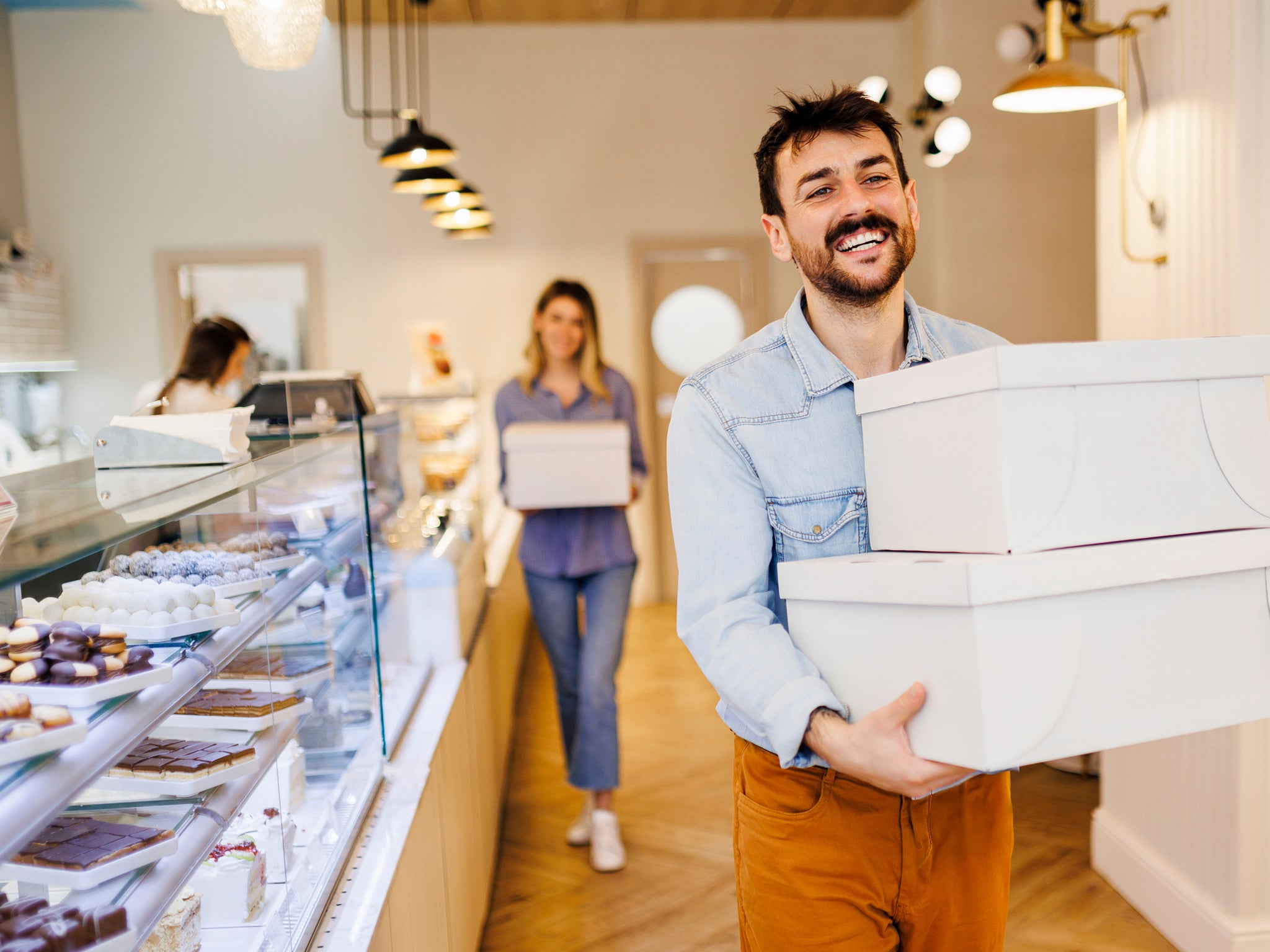 People carrying cake boxes inside a bakery