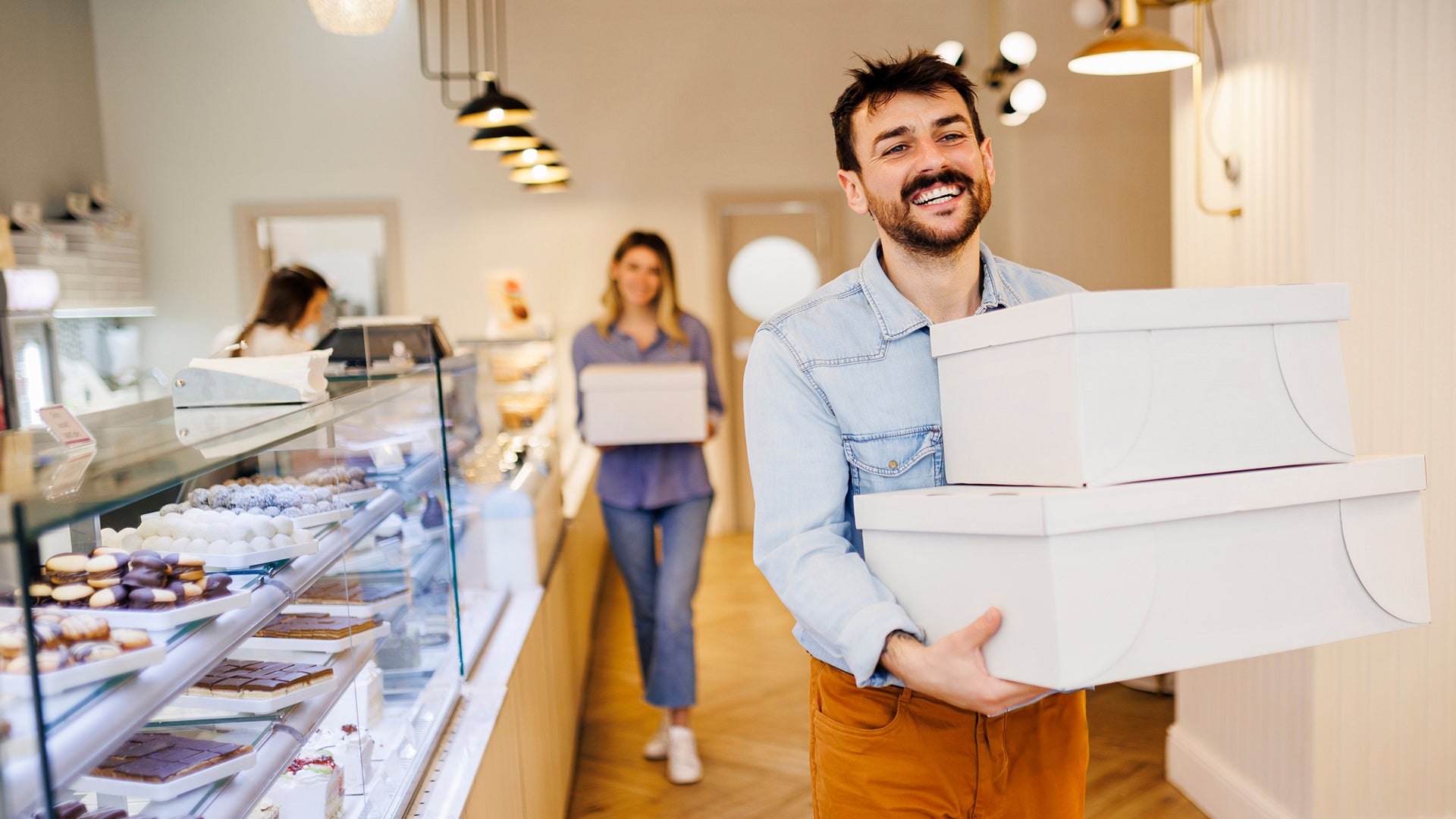 People carrying cake boxes inside a bakery
