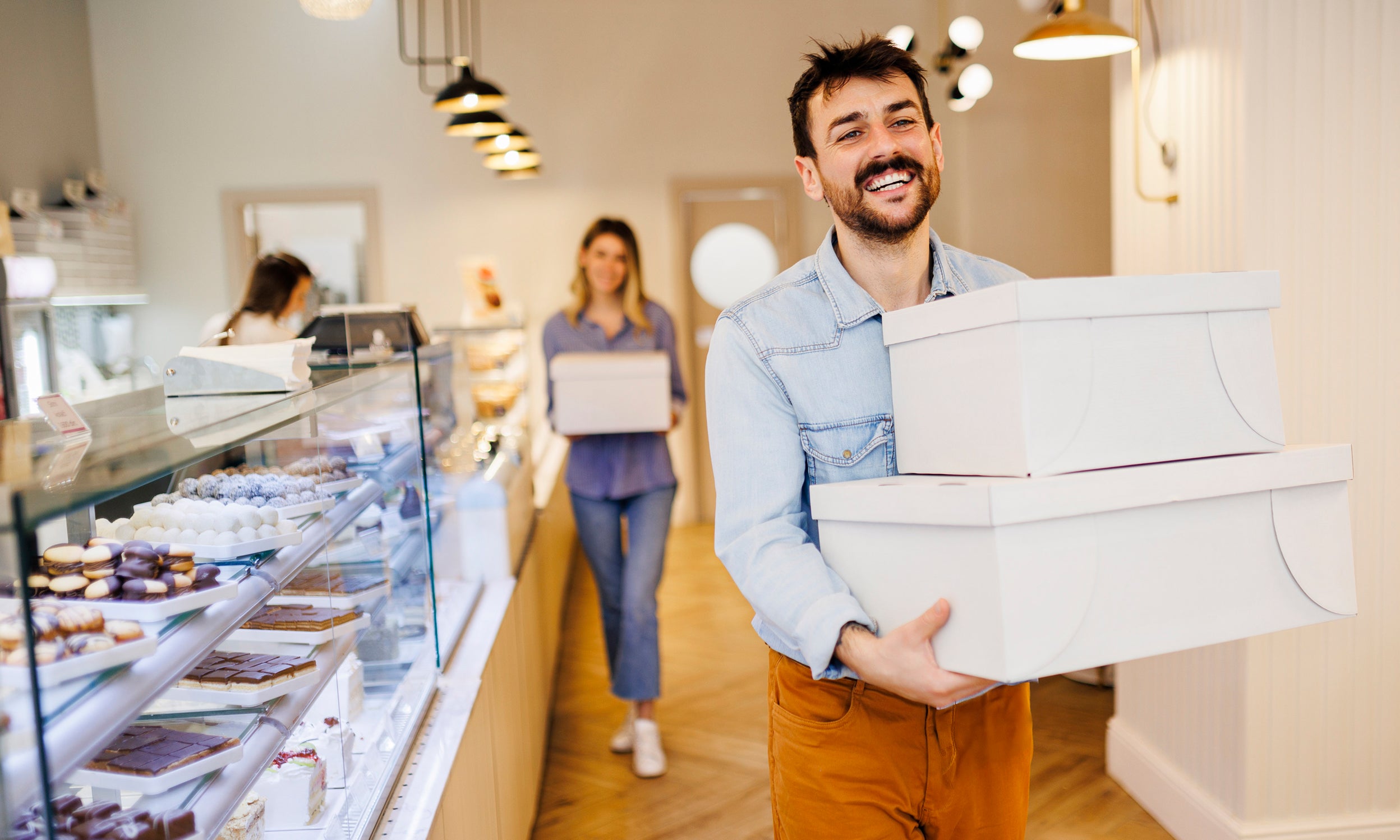 People carrying cake boxes inside a bakery