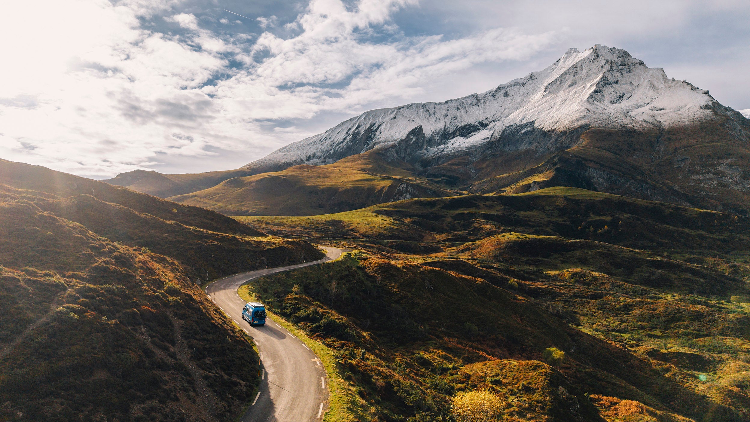 Blue vehicle driving through a mountain valley