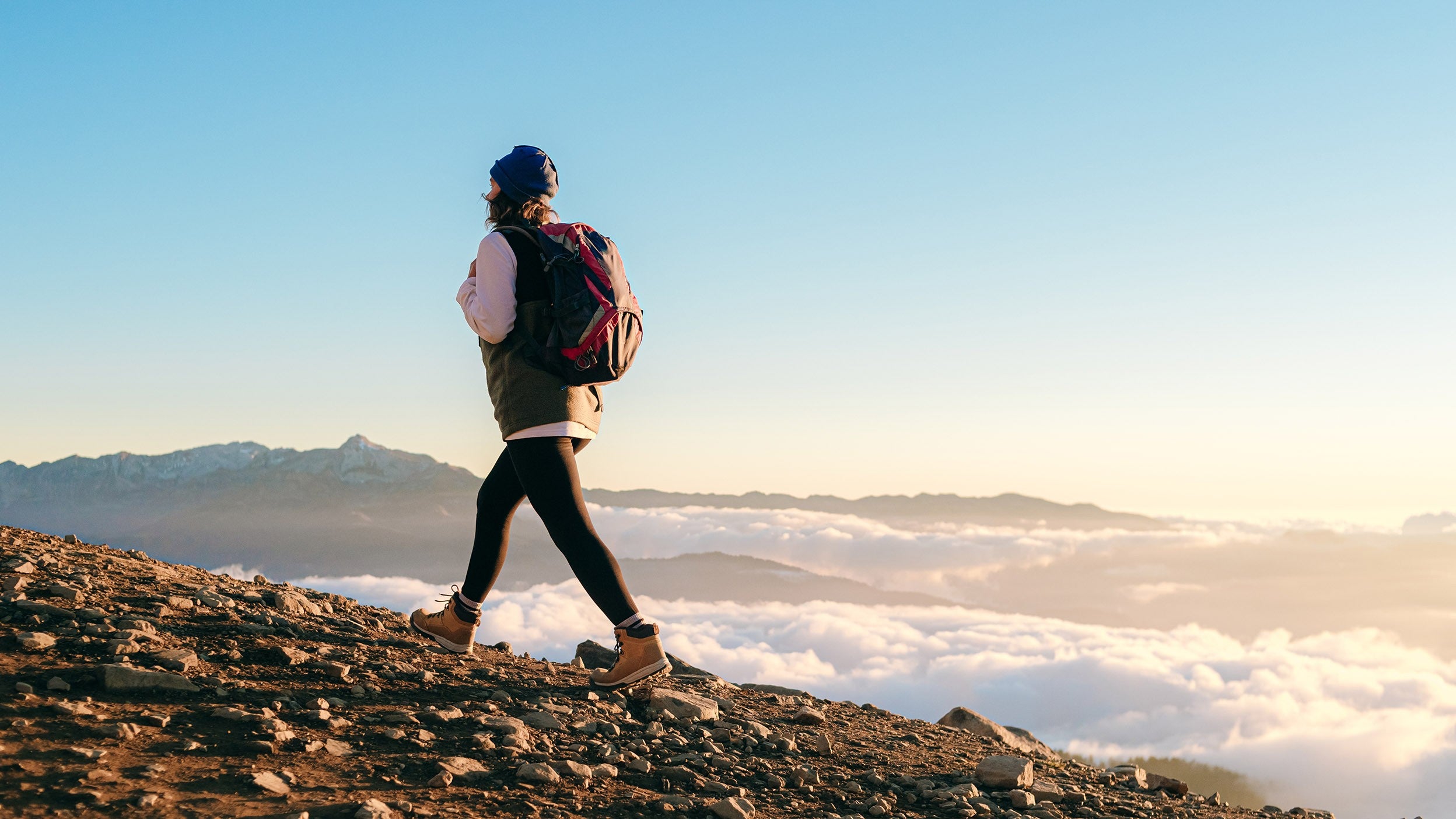 Person hiking up a rocky slope above clouds