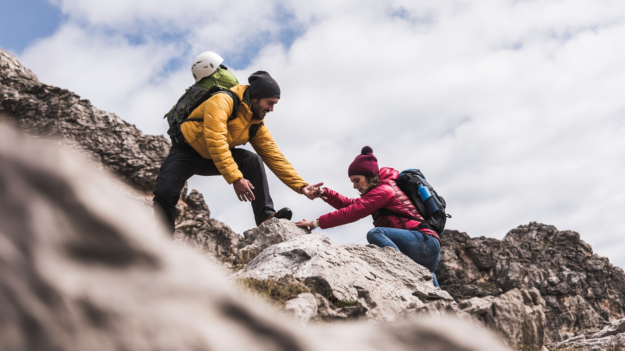 Man rock climber helping a woman up a ledge
