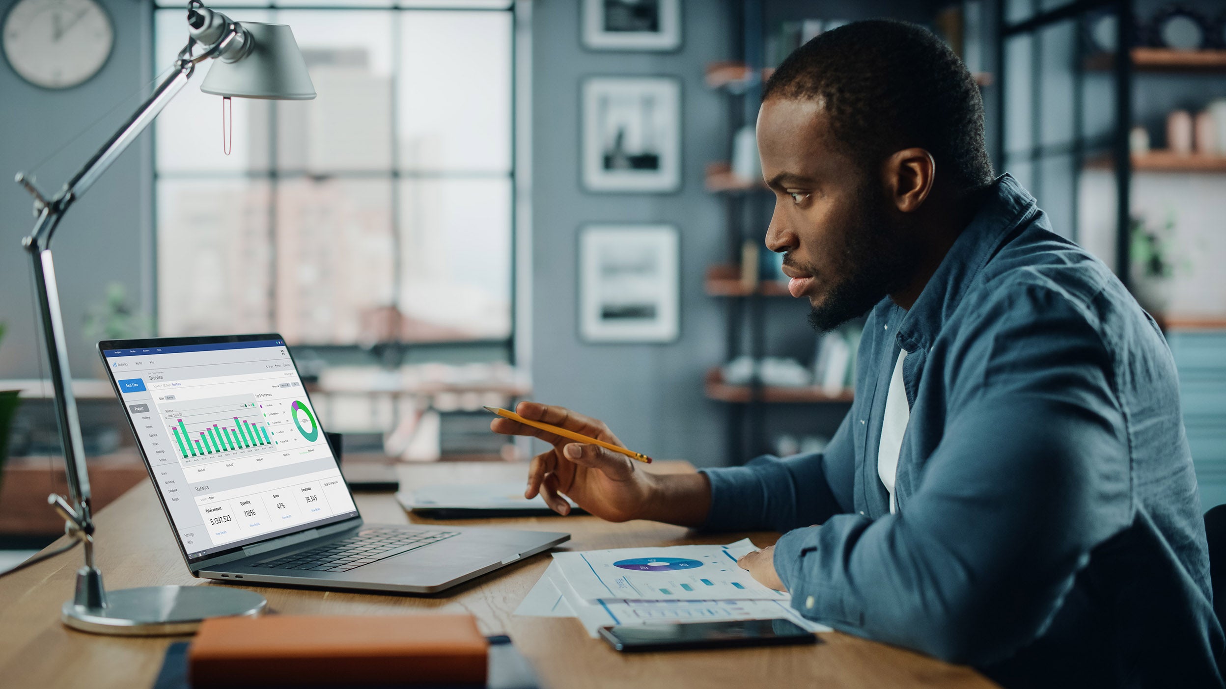 man reading statistical data from laptop and a paper 