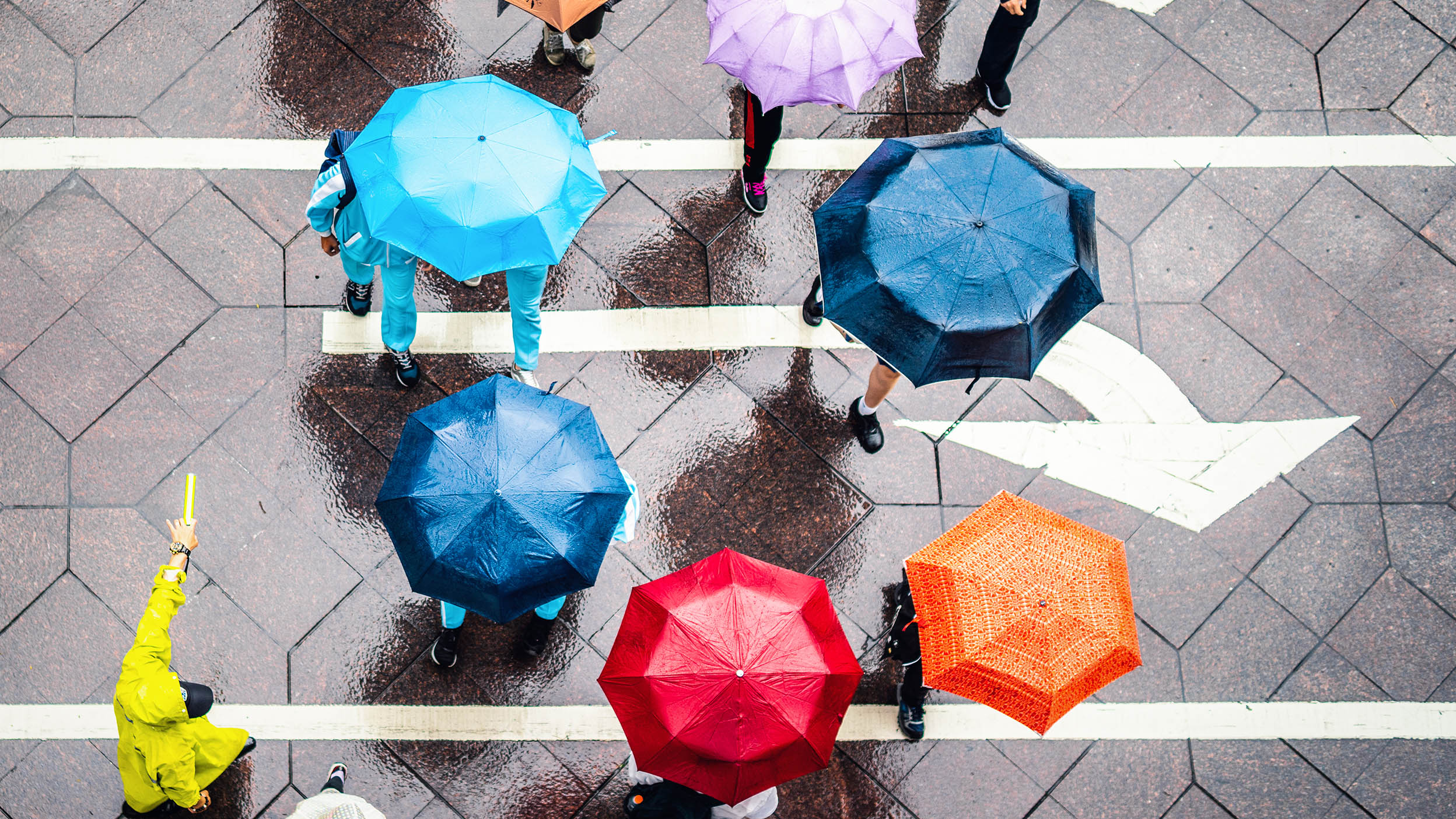 Aerial view of walking people using colorful umbrellas in rain
