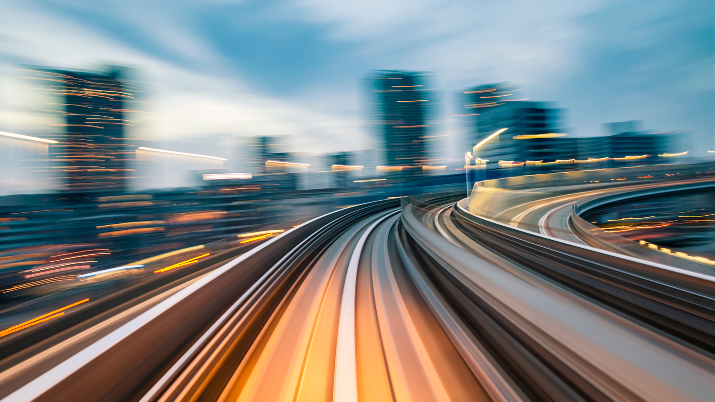 Blurred city transit tracks showing speed through a modern skyline
