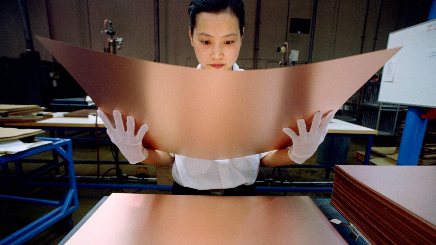 Woman inspecting copper sheet metal.