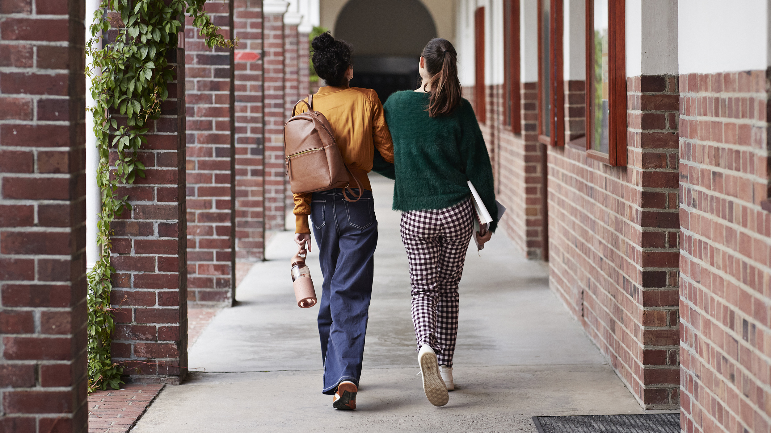 Two women arm in arm, walking down a path.
