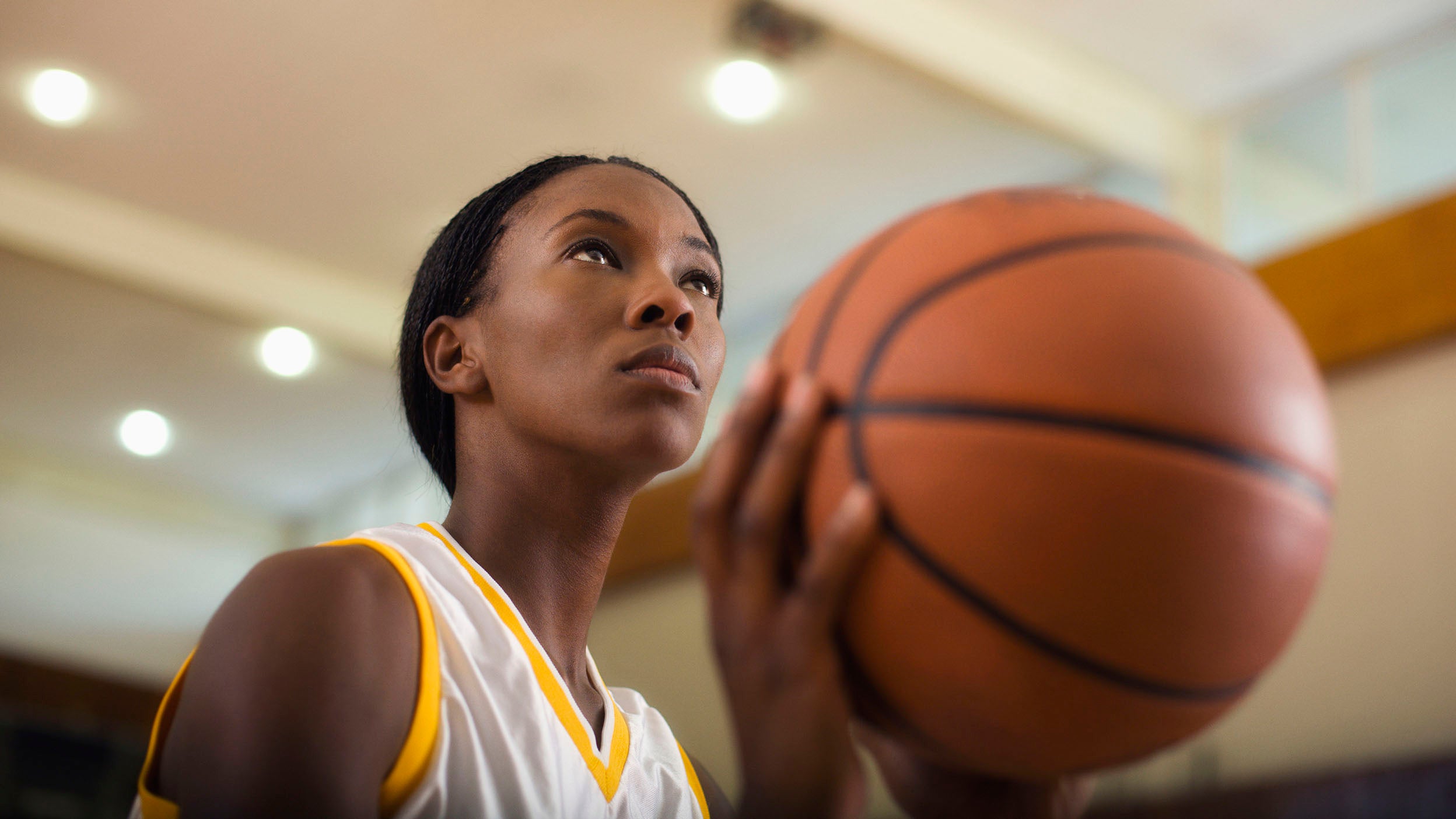 Woman basketball player about to take a shot in an indoor court.