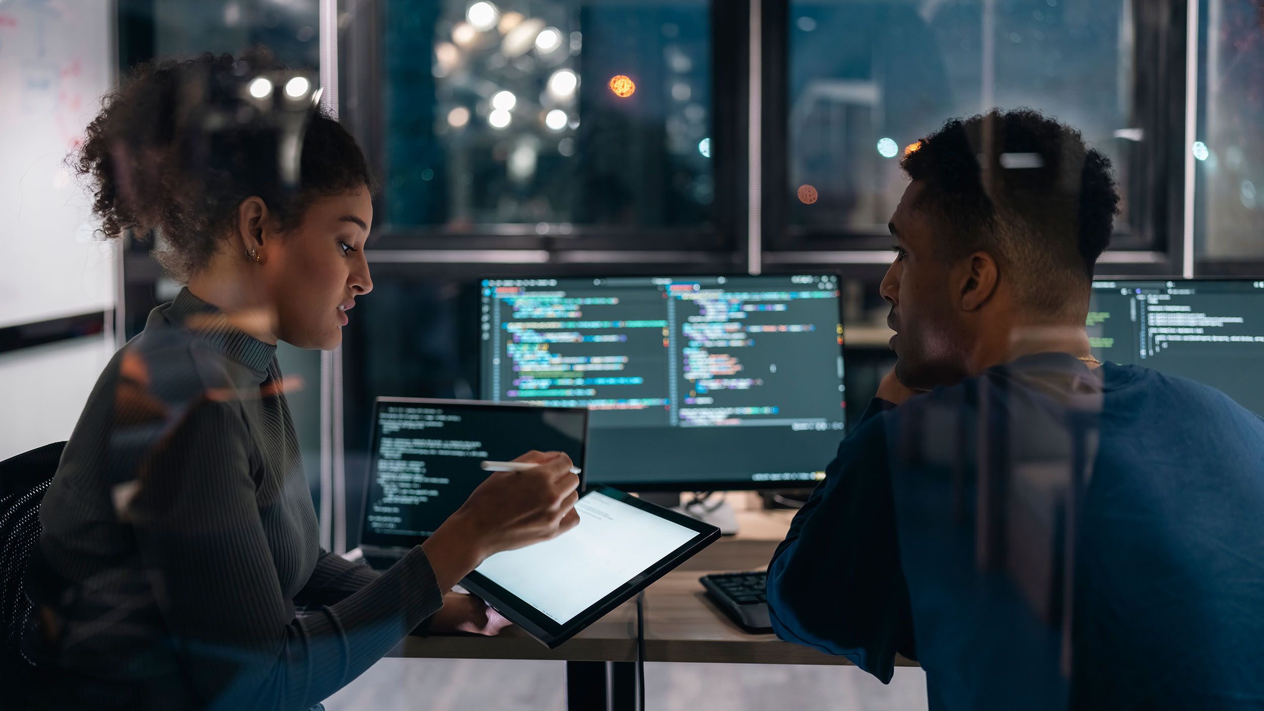Two Software developers in modern office collaborating analyzing the coding  on computer screen.