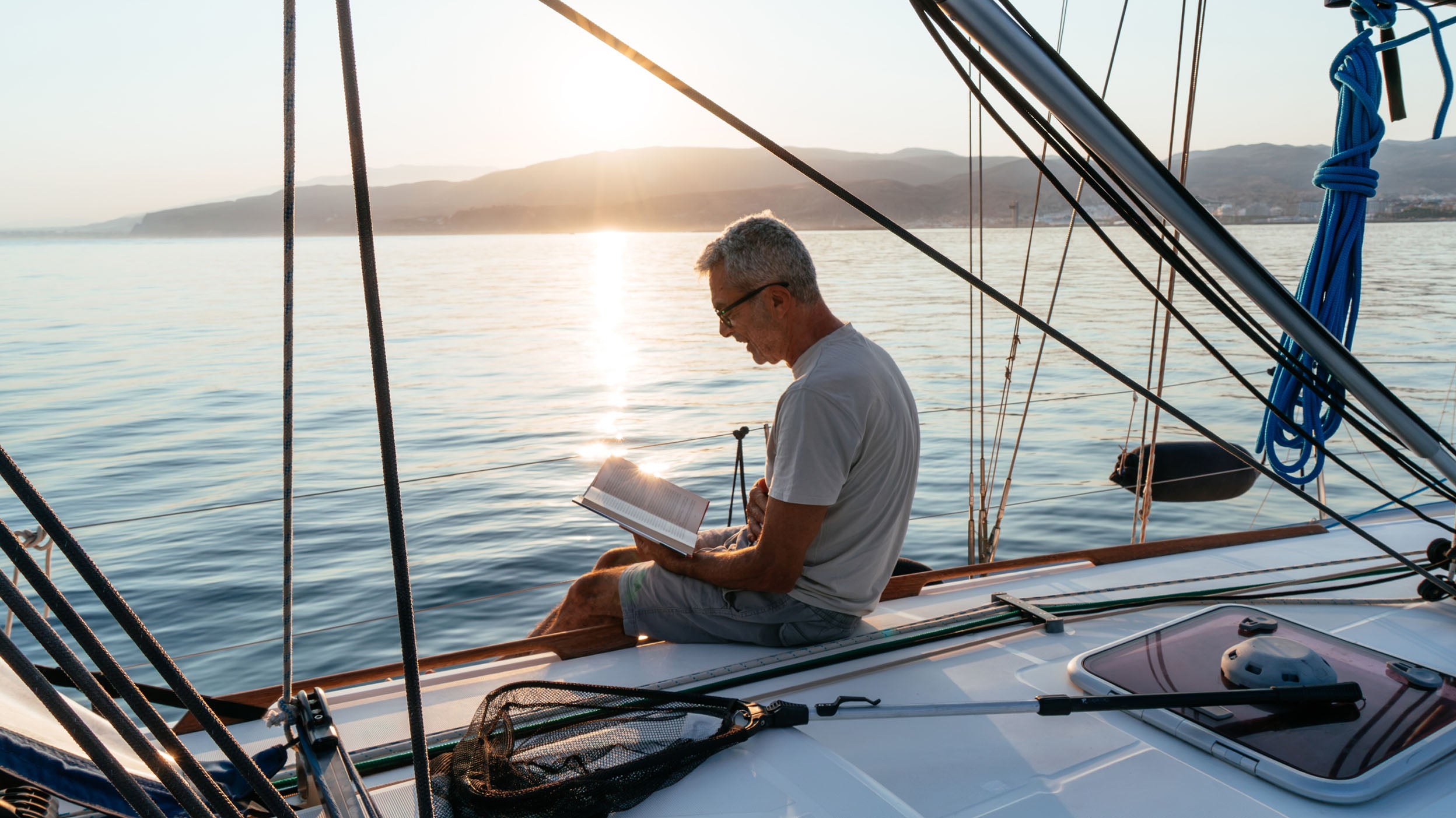 Man sitting on a boat while reading a book