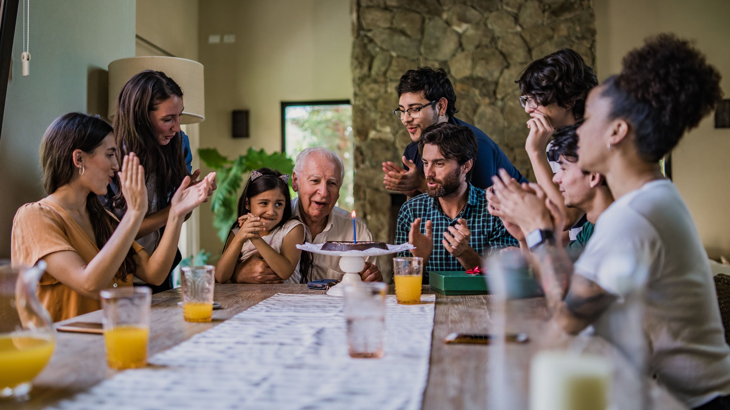 Family gathered around a birthday cake during a celebration.