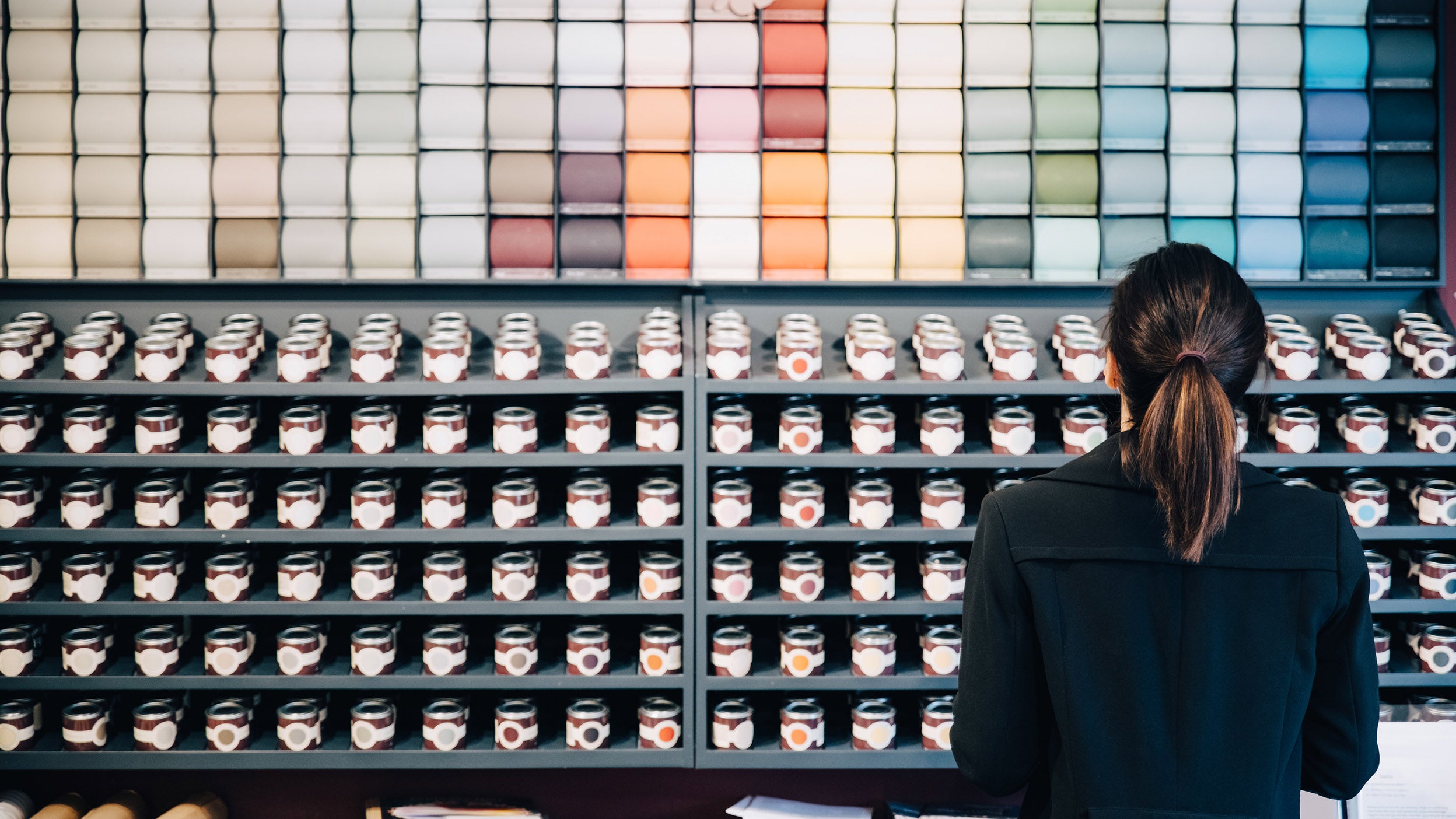 Woman choosing wallpapers and paints displayed for sale in a store 