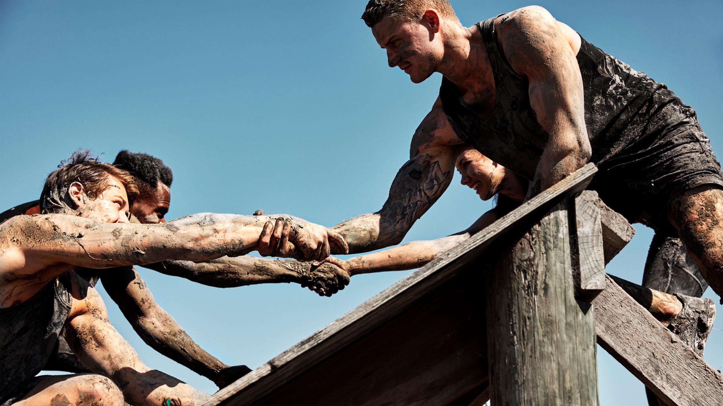 army member helping 2 people over a wall
