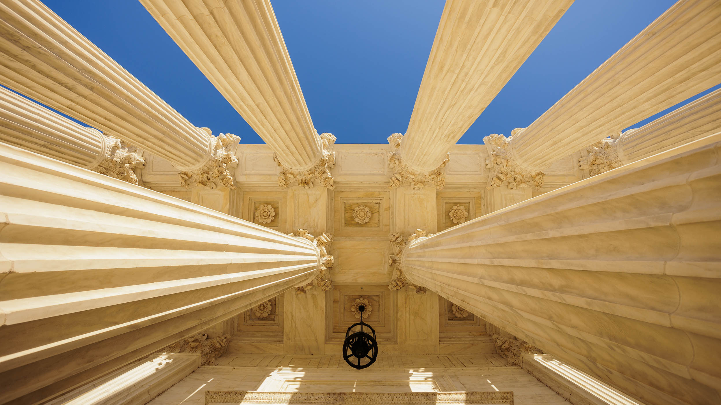 Upward view of marble columns against blue sky