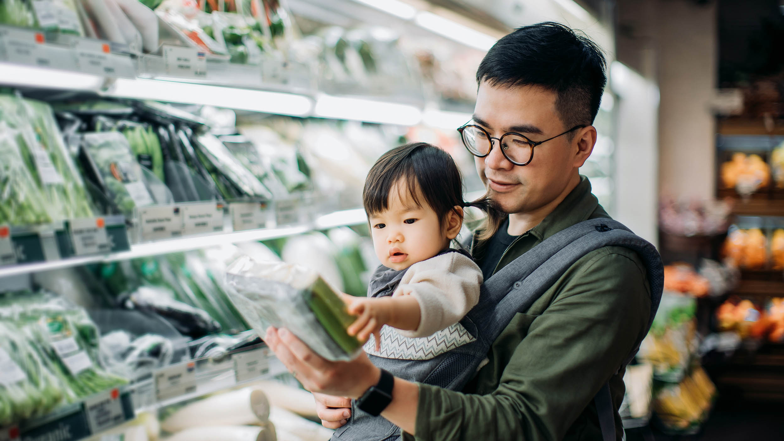 Young Asian father with cute little daughter grocery shopping for fresh organic vegetables in supermarket