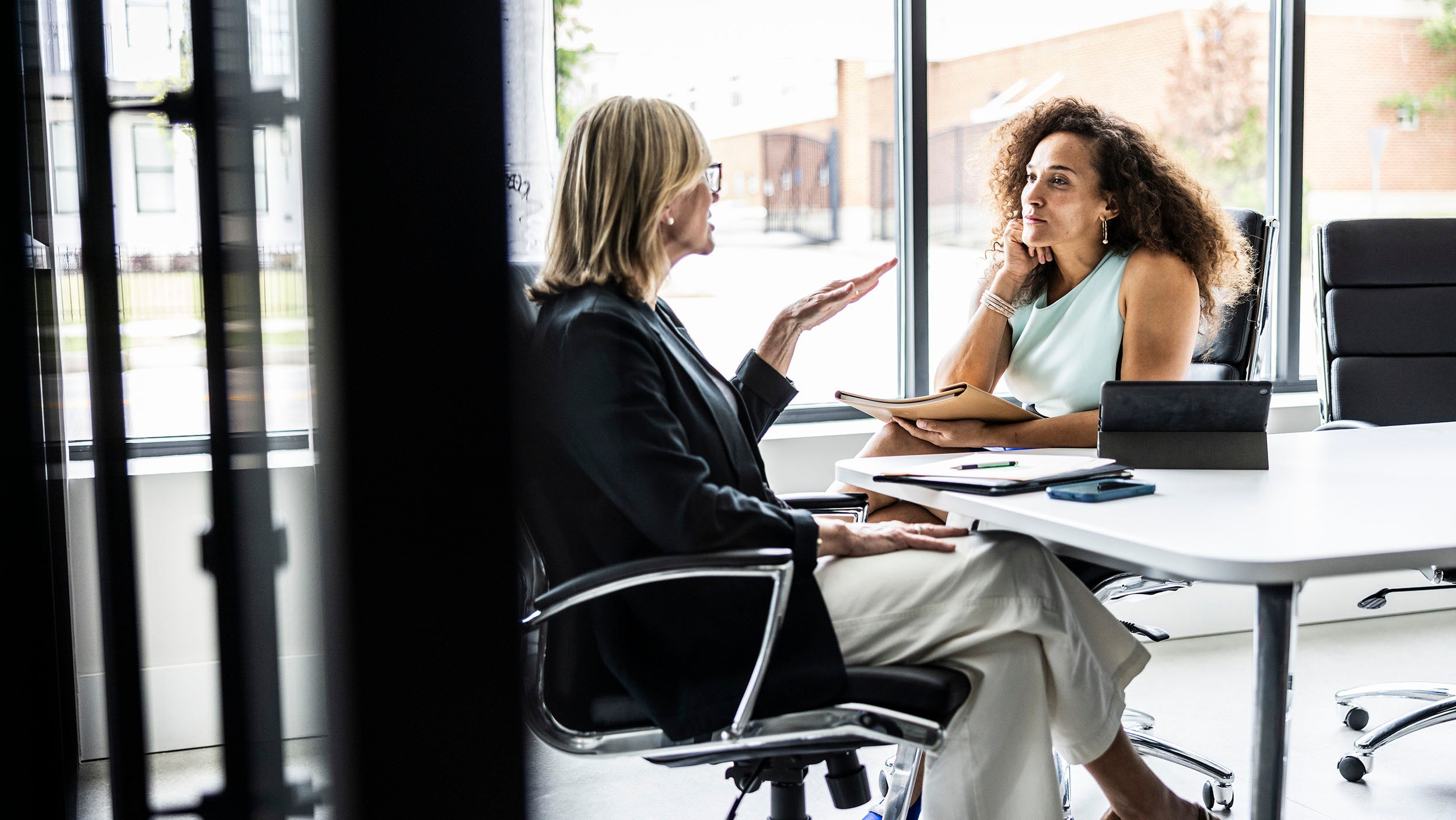 Two people having a discussion in a modern office meeting room.