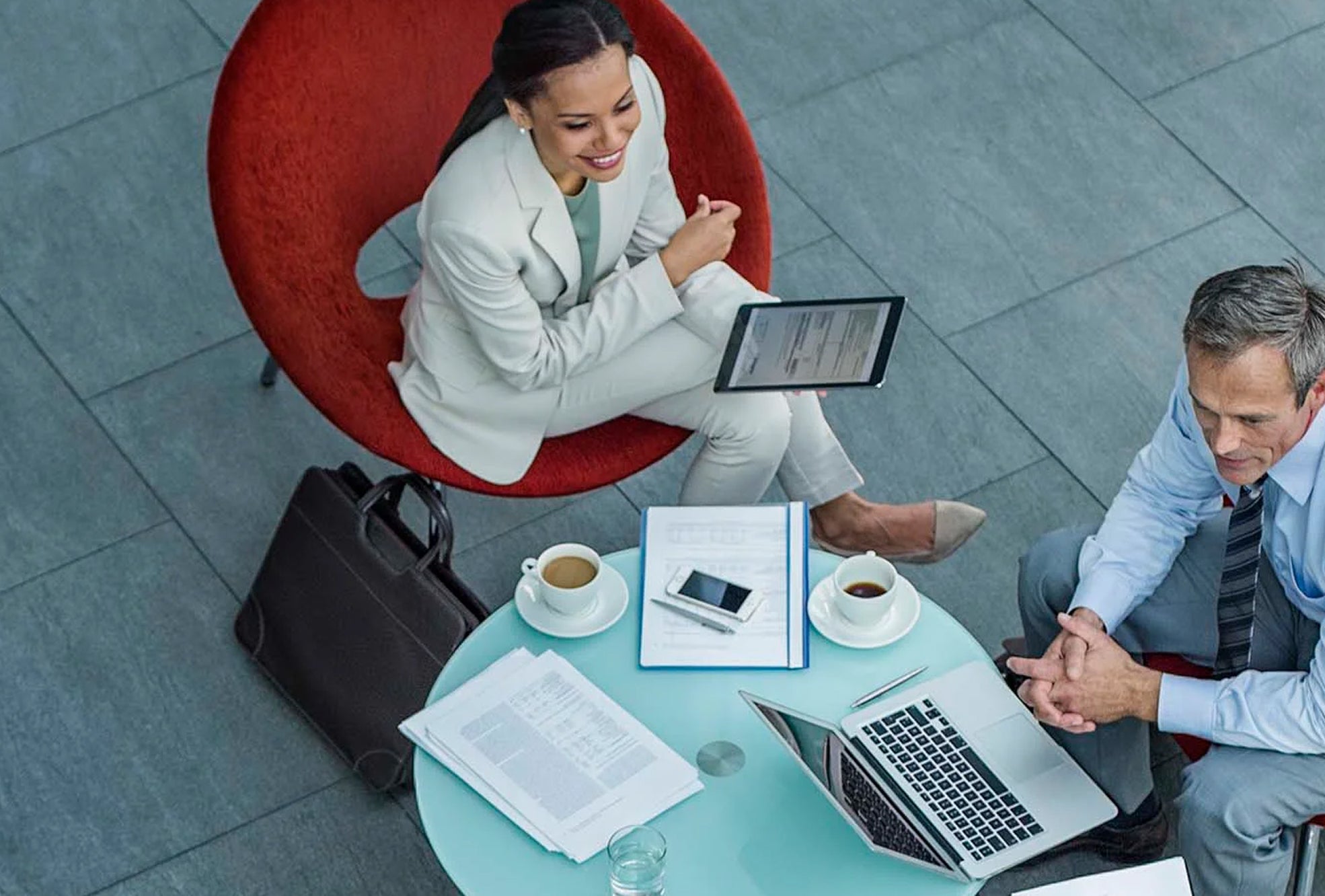 Two people sitting at table with coffee and laptops