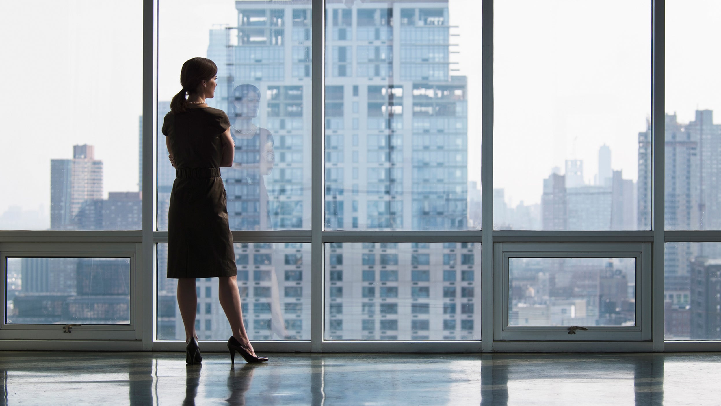 business woman looking out of a skyscraper