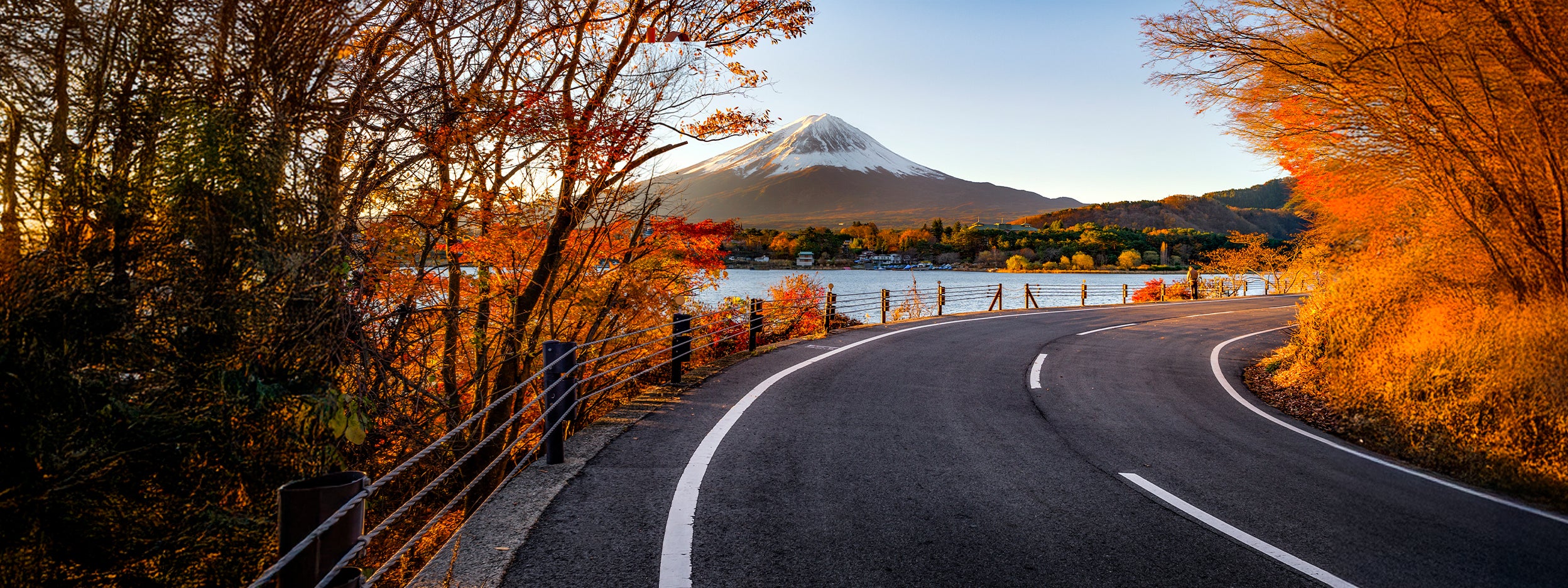 A road with lake on side with mountains
