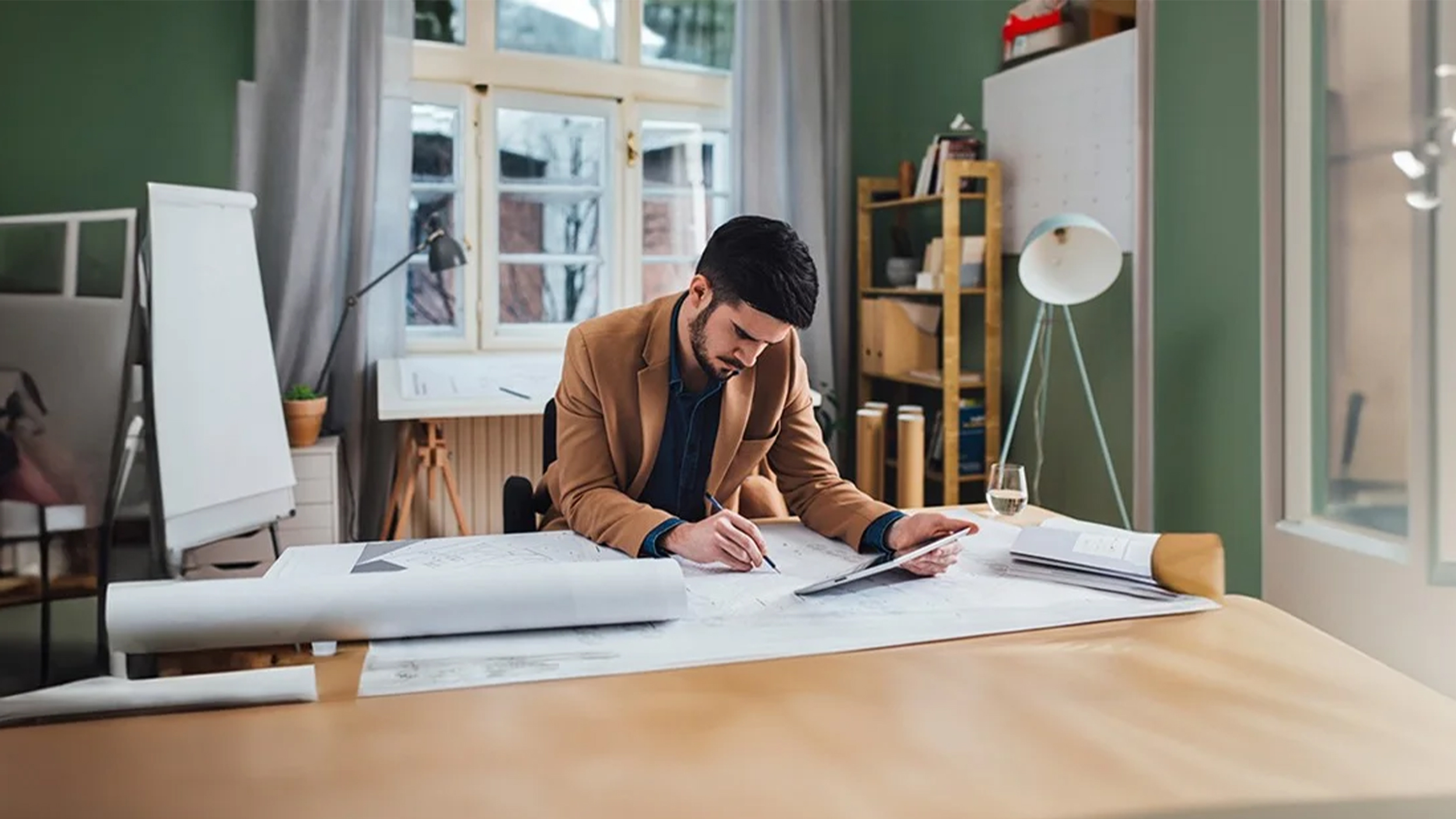 Person reviewing blueprints at a desk in modern office