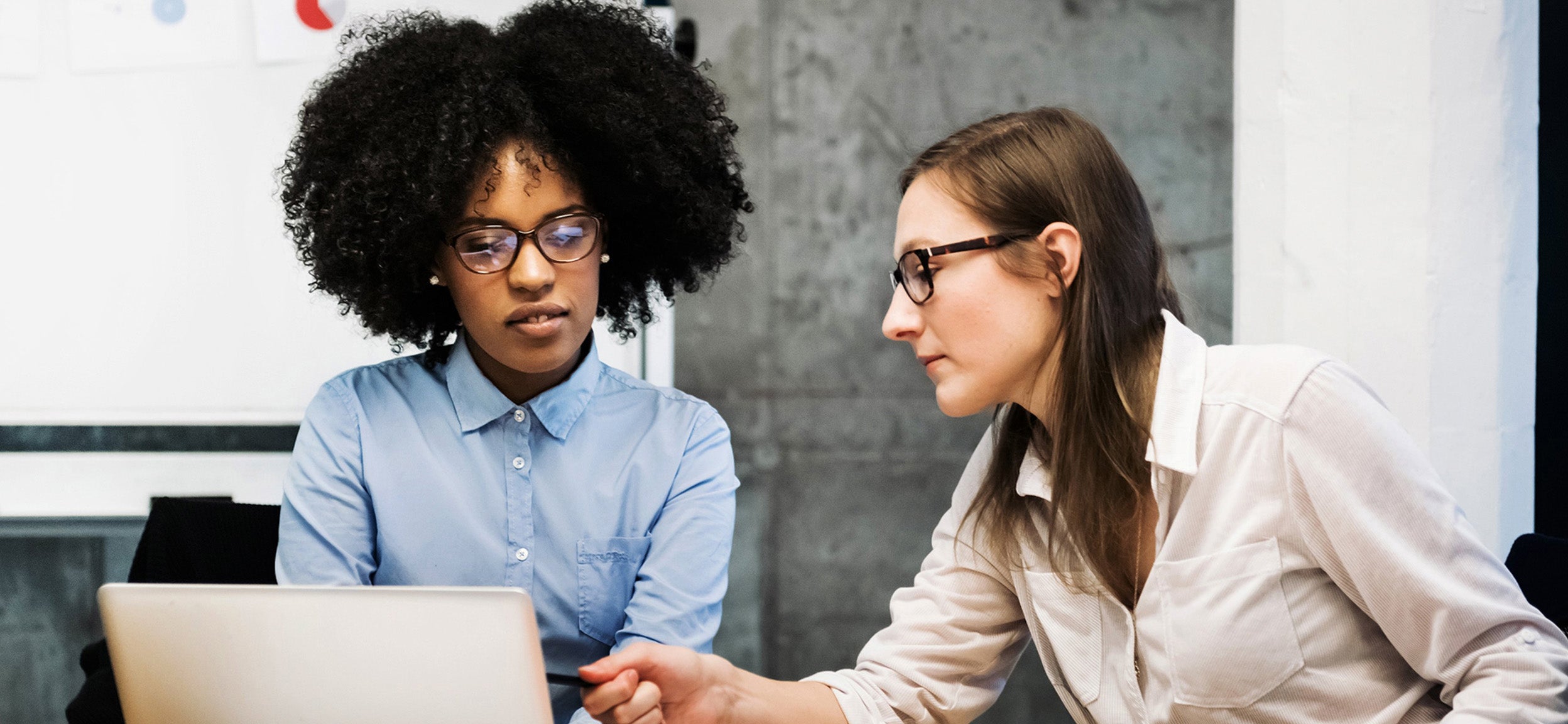Two people reviewing information in a laptop